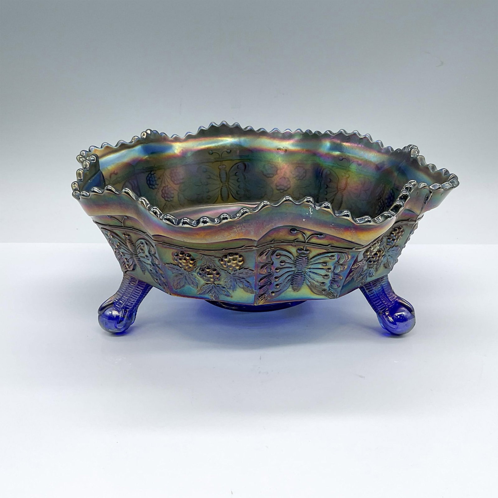 Fenton Carnival Glass Electric Blue Butterfly Bowl: A lustrous blue scalloped edge bowl beautifully adorned with embossed berries and butterflies. Dimensions: 9.5"W x 4"H Manufacturer: Fenton Country of Origin: United States