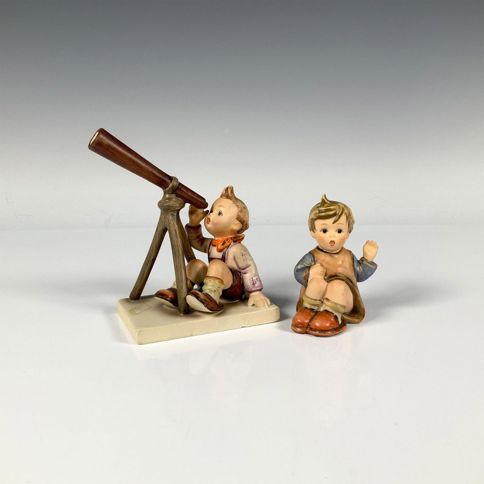 2pc Goebel Hummel Figurines, Star Gazer and I'm Here: Star Gazer (132): a boy sitting down as he is looking into a telescope and I'm Here (478): a girl sitting down and raising her hand. M.I. Hummel impressed. Goebel backstamp. Star Gazer: 4.25"L x 2.5"W