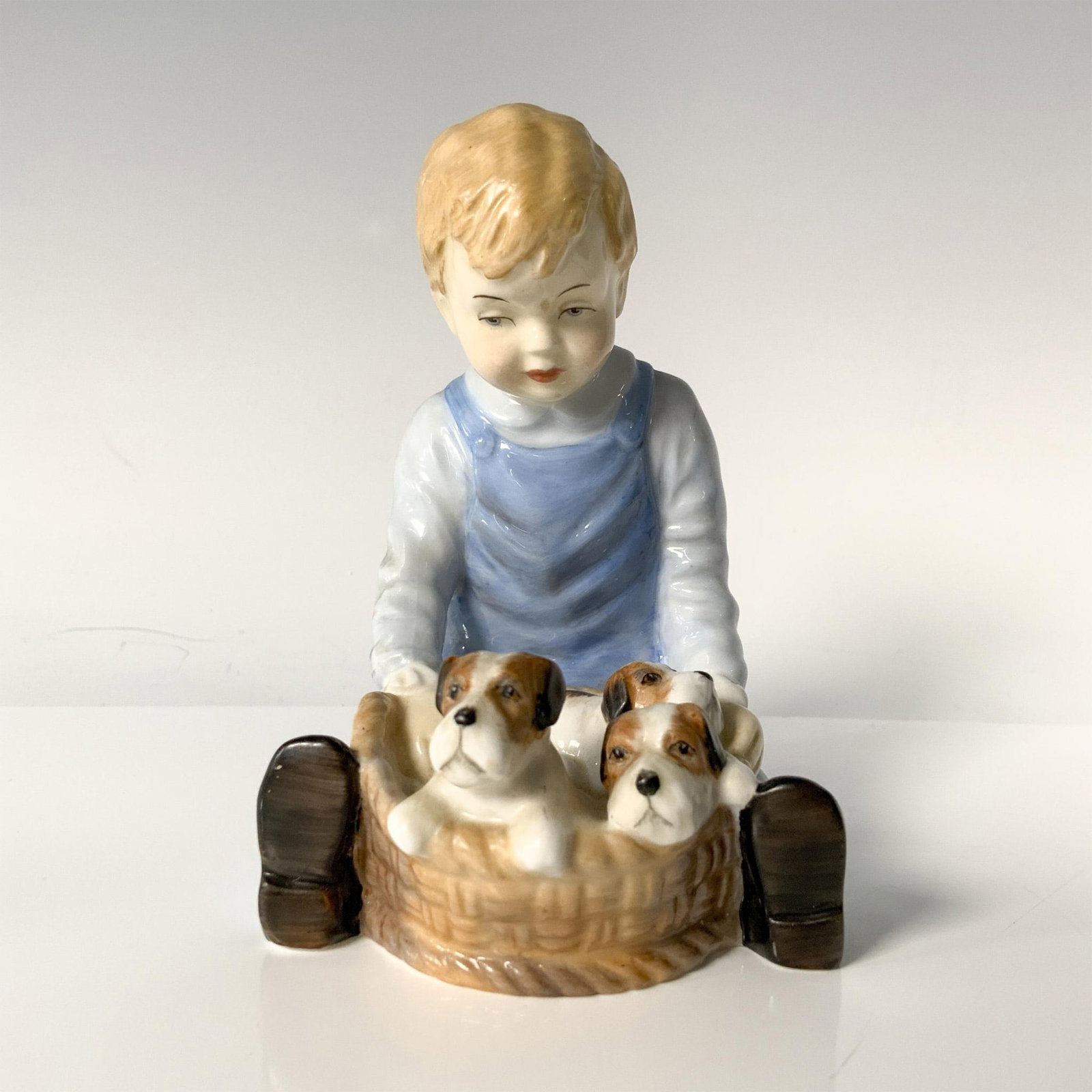 Paragon Bone China Figurine, Pals: A young blond boy, dressed in blue shirt and overalls, marvels at a basket of adorable newborn puppies. Paragon backstamp. Dimensions: 3"L x 2.75"W x 4"H Manufacturer: Paragon Country of Origin: Engla