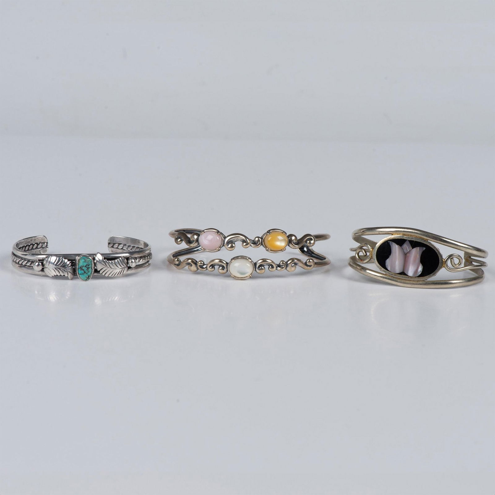 3pc Fancy Sterling Silver Gemstone Cuff Bracelets: The fist bracelet tested sterling silver and has a turquoise stone. The second bracelet tested sterling silver and has three different color stones. The third bracelet tested sterling silver and is st