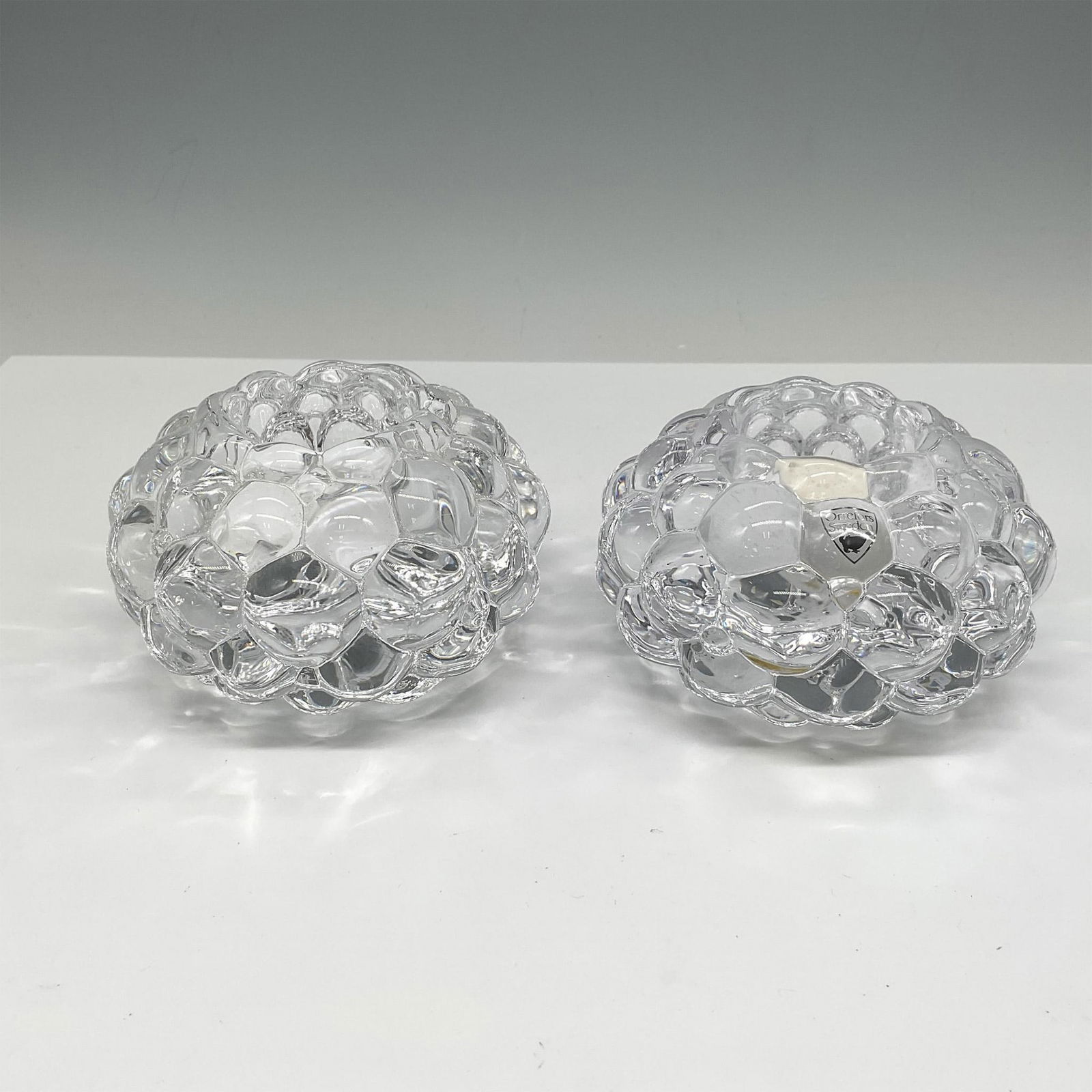 Pair of Orrefors Crystal Hallon-Raspberry Votives: Crystal design of stacked drupelets creates these visually soft and appealing holders. Orrefors mark. 6475762. This item has its original box: 4.75"L x 4.75"W x 3"H. Artist: Anne Nilsson Issued: 21st
