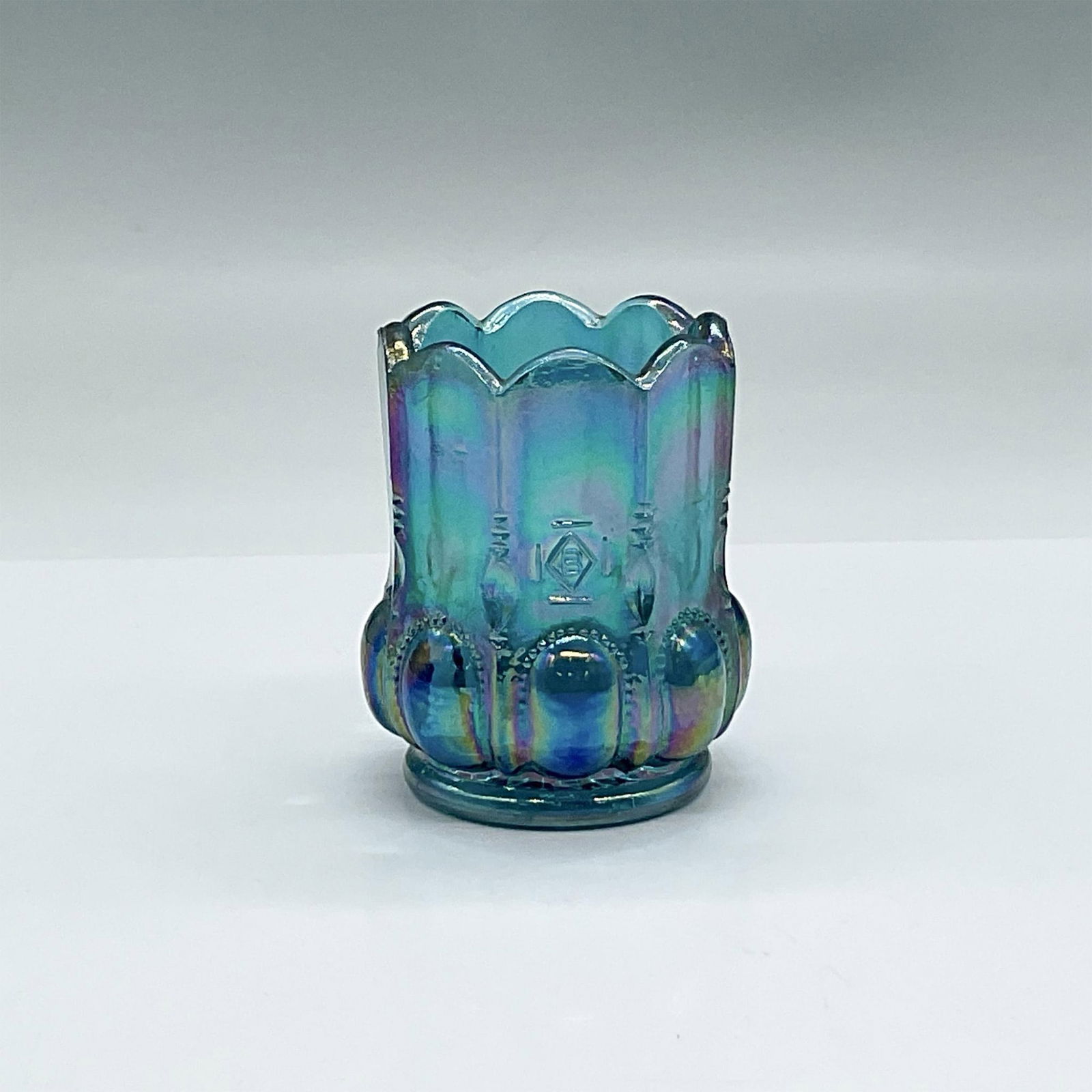 US Glass, Blue Carnival Glass Toothpick Holder: From the Michigan line. The blue carnival glass gives the toothpick holder a beautiful sheen. Issued: 20th c. Dimensions: 2.25"dia. x 2.75"H Manufacturer: US Glass Country of Origin: USA