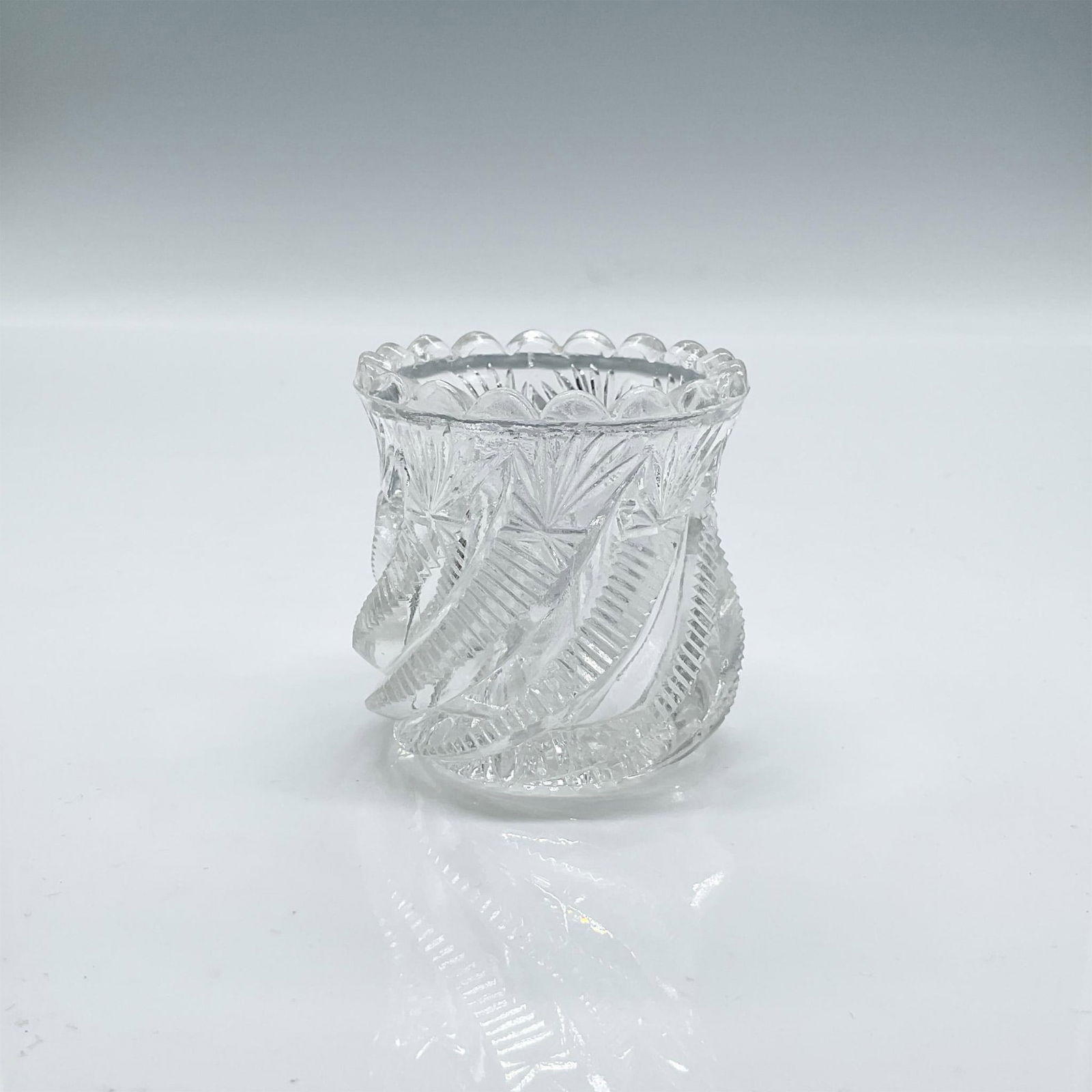 Bryce, Higbee Glass Toothpick Holder: Clear glass toothpick holder engraved in a swirled latter-type design with a fan design at the top end with a scalloped rim. Dimensions: 2.25"H x 2.1"dia Manufacturer: Bryce, Higbee