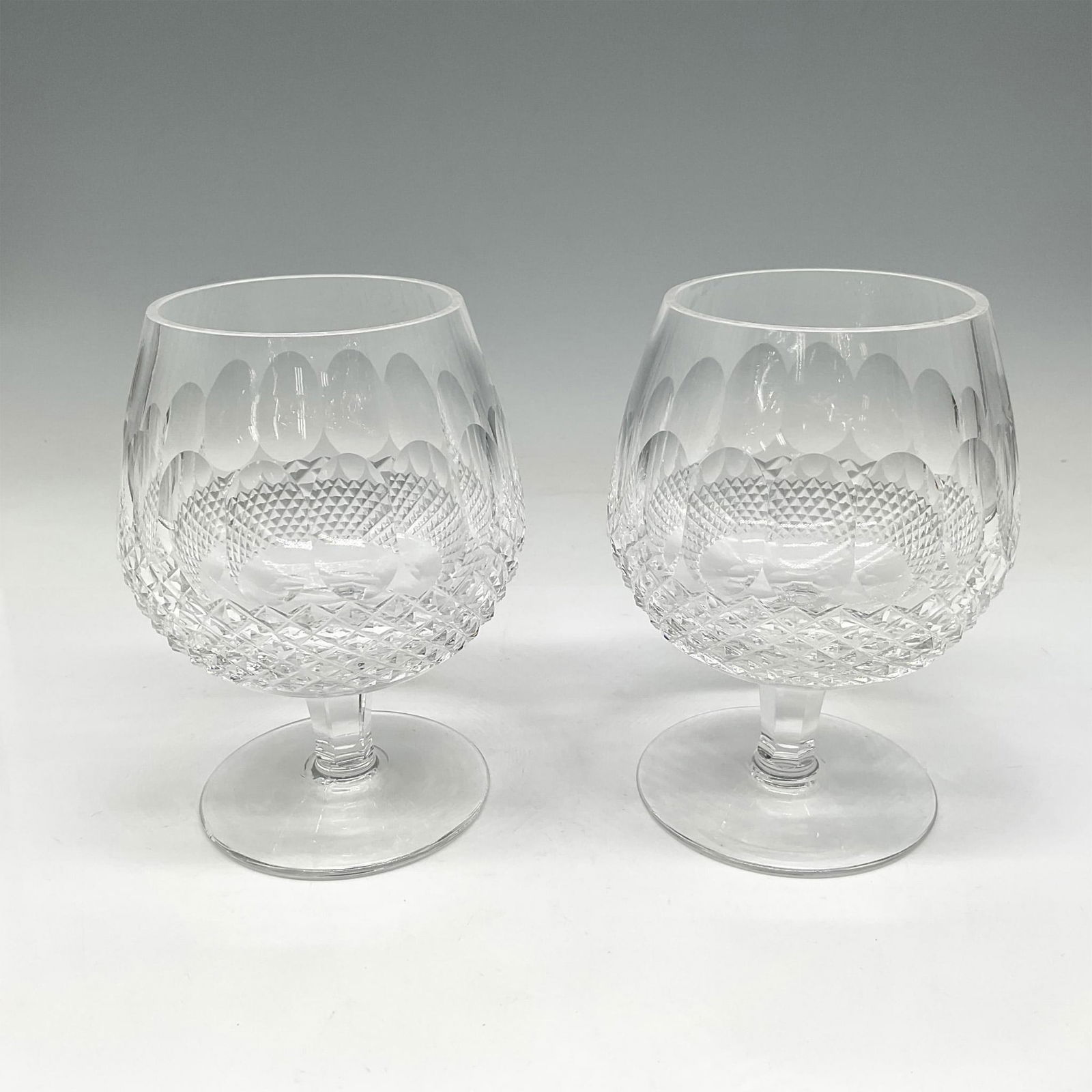 Pair of Waterford Crystal Colleen Short Stem Brandy Glasses: Beautifully cut with thumbprint and crosshatch design on clear base. Waterford acid mark. Issued: 20th century Dimensions: 5.25"H x 3.75" dia. Manufacturer: Waterford Country of Origin: Ireland