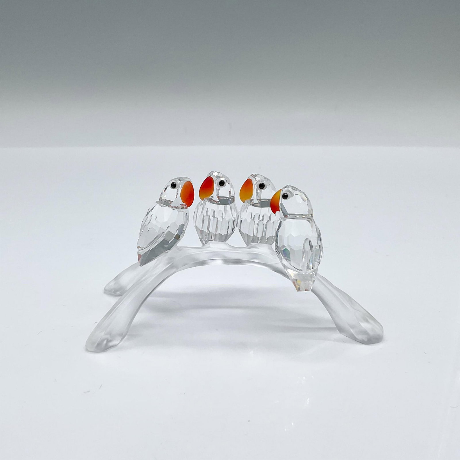 Swarovski Crystal Figurine, Lovebirds Baby: Part of the Feathered Beauties theme. Four tiny cute birds, clear bodies with fire opal crystal beaks, perched on a frosted branch. Swarovski marked. Artist: Adi Stocker Issued: c. 1996-2011 Dimension
