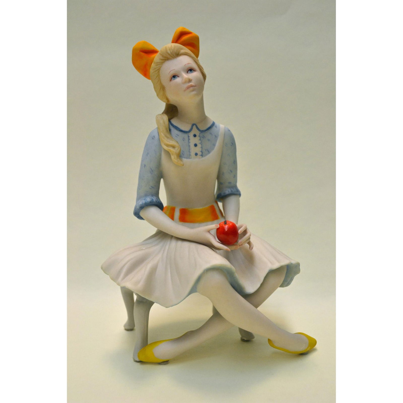 Cybis Porcelain Pollyanna Figurine: Bisque Porcelain Decorated, hand created, hand painted by the Artists of the Cybis Studios. Featuring Pollyanna seated, holding an Apple in her hand. Design Number: 465. Authentic Backstamp on the und