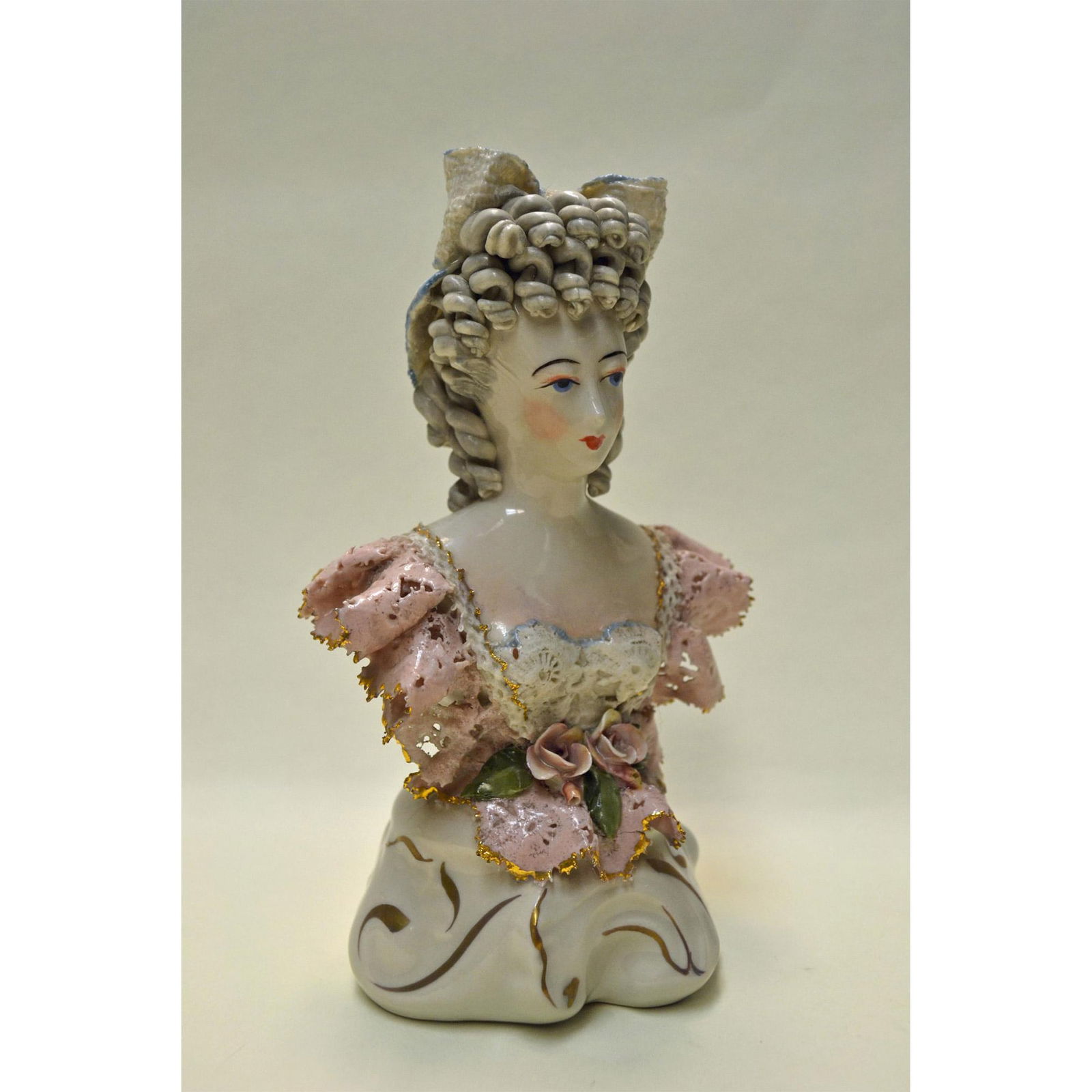 Cordey Porcelain Lady Bust In Lace W/Bow: Bisque Glazed Porcelain, hand created, hand painted by Bolesaw Cybis. Early and Rare featuring a Lady Figurine with a Large Lace Bow in her hair tipped in Pastel Blue. Pink Lace off the Arms, forms th