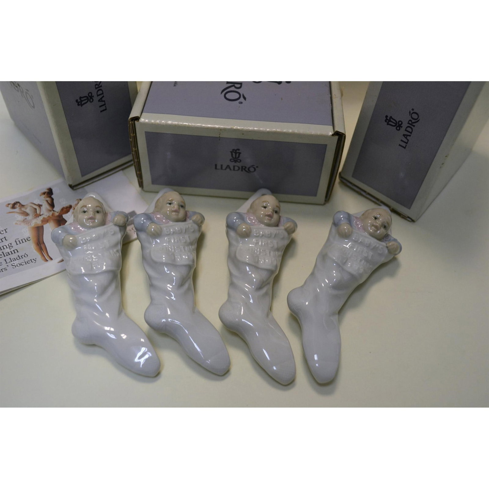 4Pc Lladro Porcelain Baby's First Christmas Ornament, 1991: Fine Porcelain Glazed, Decorated, featuring Baby's First Christmas Ornament. A collection of four (4) hand made, hand painted by the Artisans of the Lladro Studios. Baby in a Stocking. Hallmark: 5839.