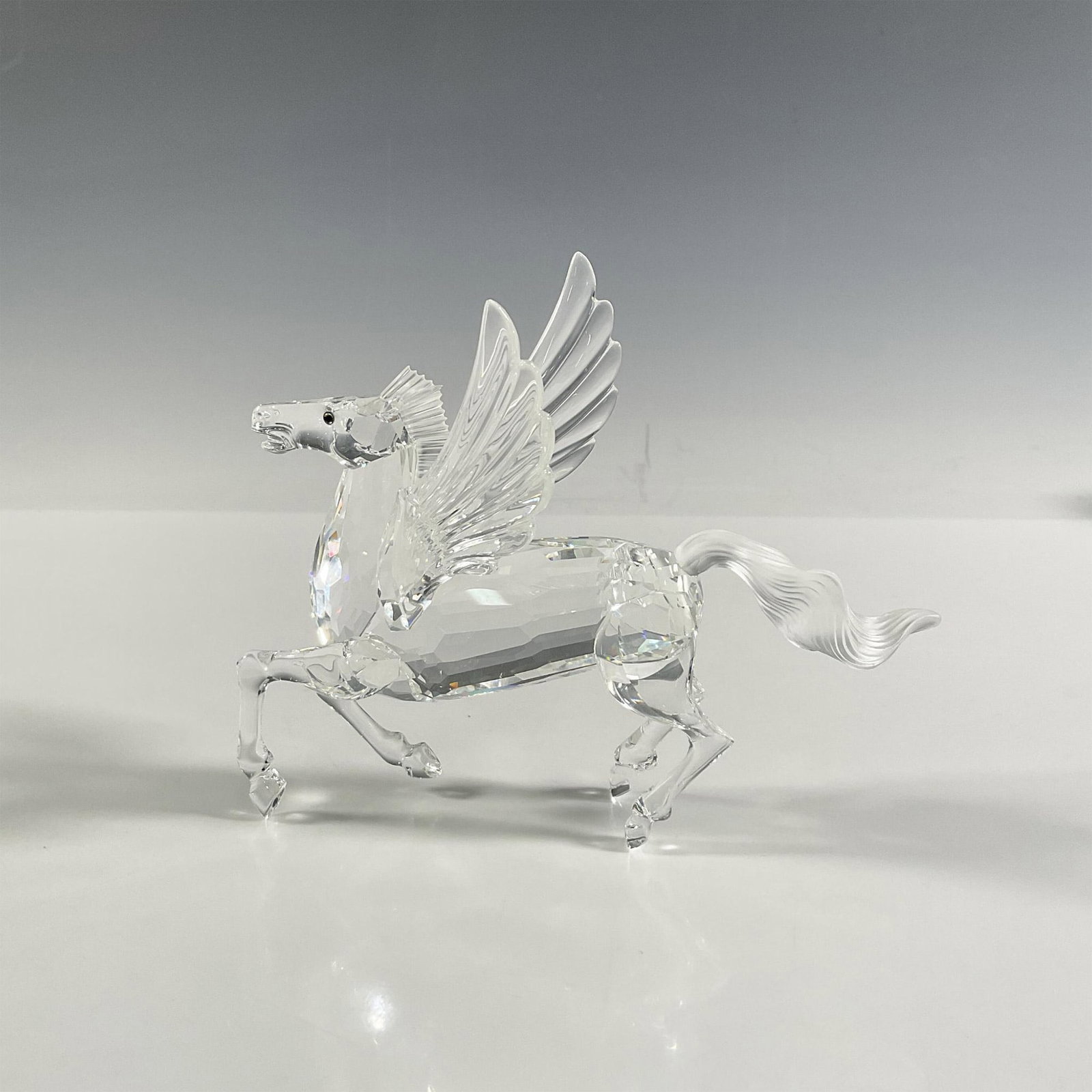 Swarovski Crystal Figurine, The Pegasus: A clear figural of a majestic winged horse with a frosted tail and topaz colored eyes. 1998 Swarovski Crystal Society edition. Part of the Fabulous Creatures trilogy. Swarovski marking. This item has 