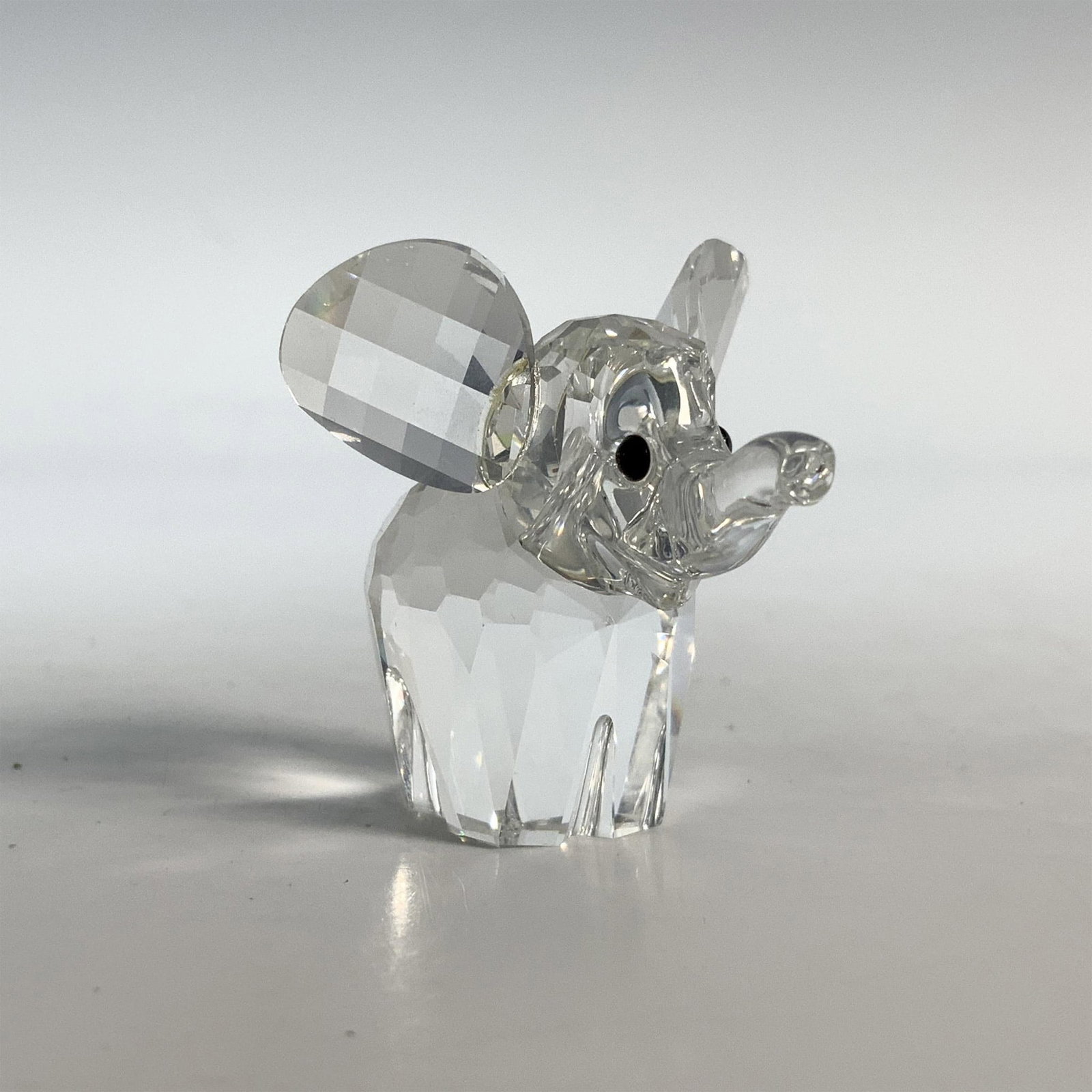 Swarovski Silver Crystal Elephant Figurine, 7640 NR 040 000: Trumpeting pachyderm with a clear cut crystal body and black eyes. This item has its original box which measures 2.5"H x 3.25" dia. Acid etched Swarovski backstamp. Issued: 20th Century Dimensions: 1.