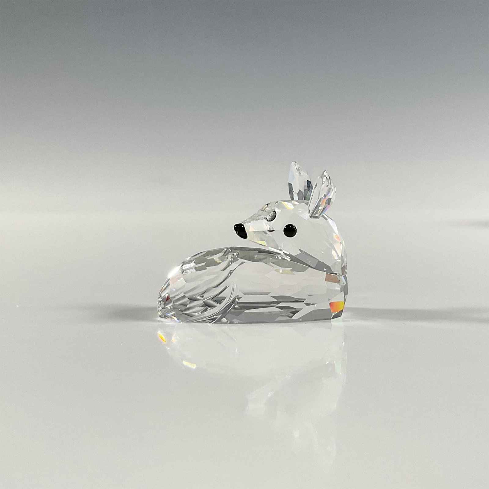 Swarovski Silver Crystal Fawn Figurine: A clear faceted figure of a young deer laying down. Part of the Woodland Friends collection. Swarovski marking. This item has its original box: 3.25"W x 3.75"H. Artist: Edith Mair Issued: 1994-1998 Di