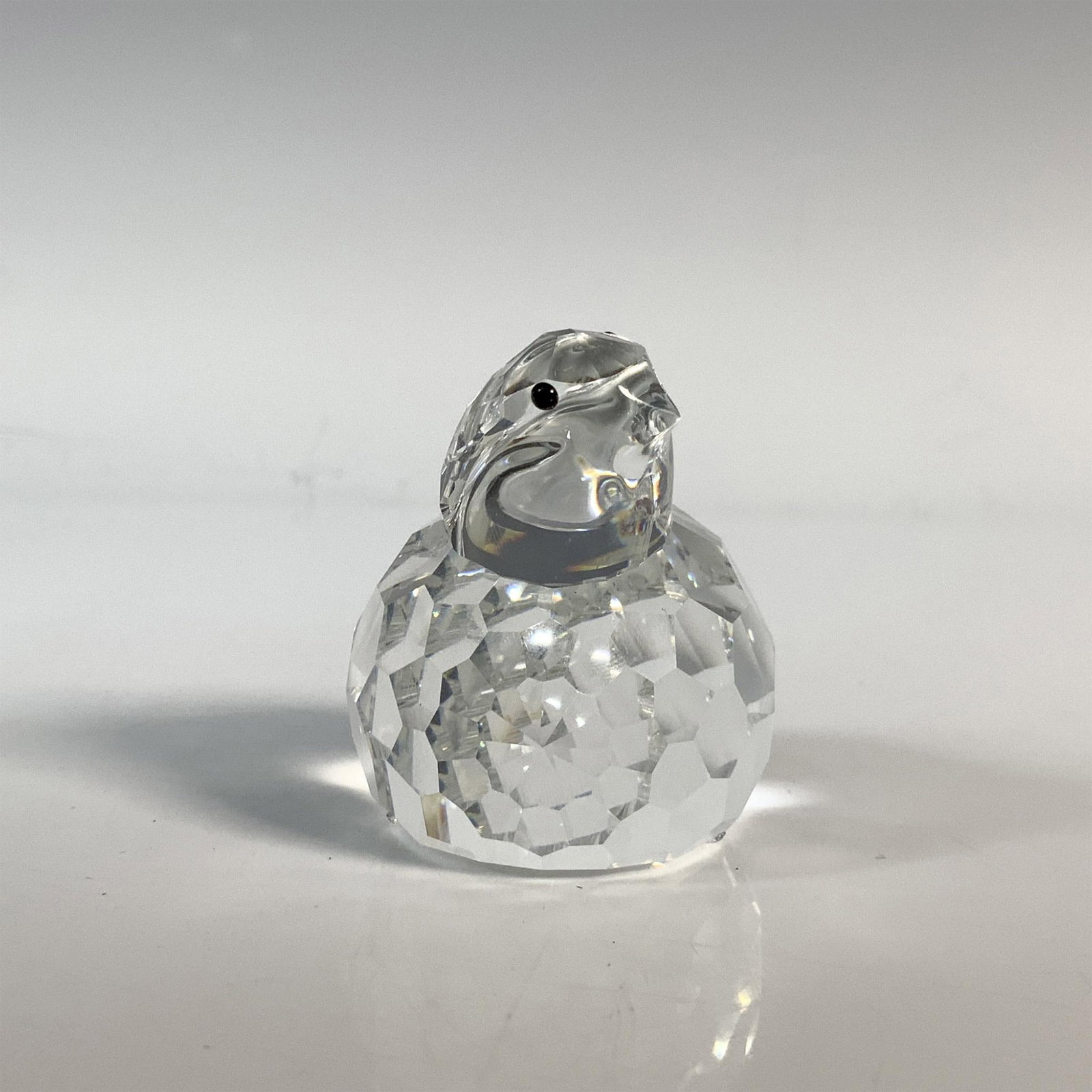 Swarovski Silver Crystal Quail Figurine, 7625 NR 50: The bird is resting on the ground looking inquisitively upward. It has a clear cut crystal body with black eyes. This item has its original box which measures 4"H x 5" dia. Acid etched Swarovski backs