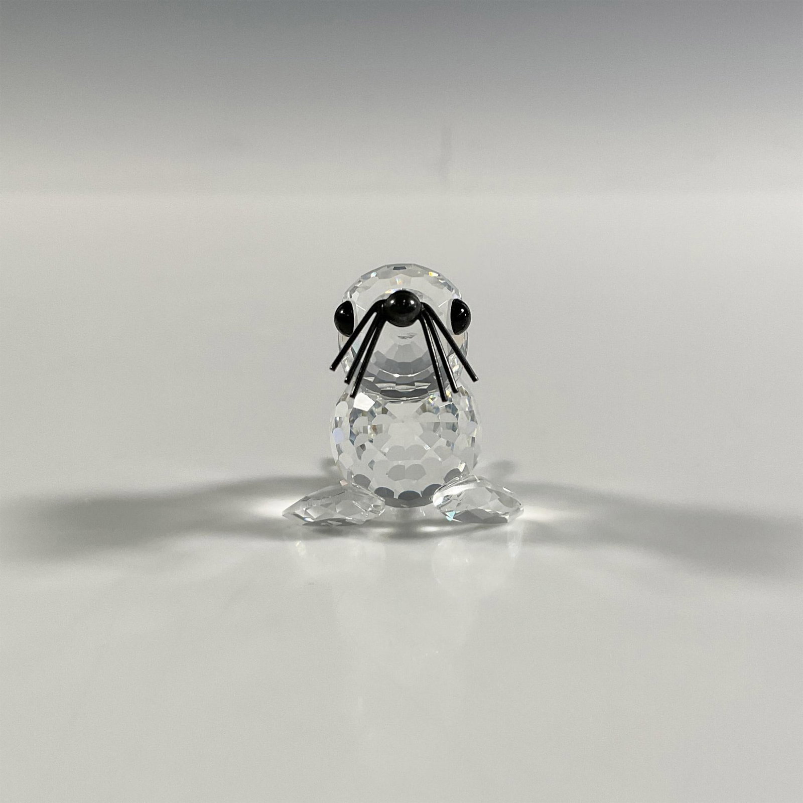 Swarovski Silver Crystal Miniature Seal Figurine: A clear faceted figure of a seal with black eyes and a metal nose and whiskers. Swarovski marking. This item has its original box: 3.25"W x 2.5"H. Dimensions: 1.5"L x 1.25"W x 1.25"H Manufacturer: Swa