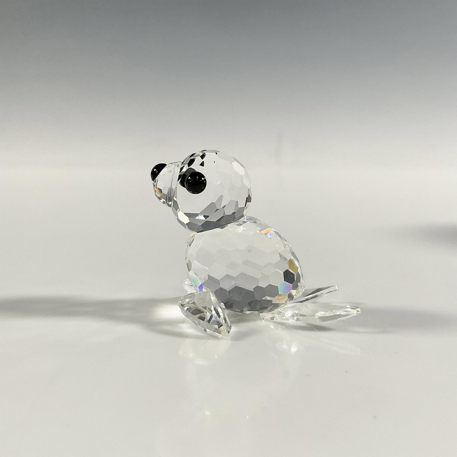 Swarovski Silver Crystal Seal Pup Figurine: A clear faceted figure of a baby seal with black eyes and nose. Swarovski marking. This item has its original box: 2.5"W x 2.75"H. Dimensions: 1.5"L x 1.25"W x 1.25"H Manufacturer: Swarovski Country o
