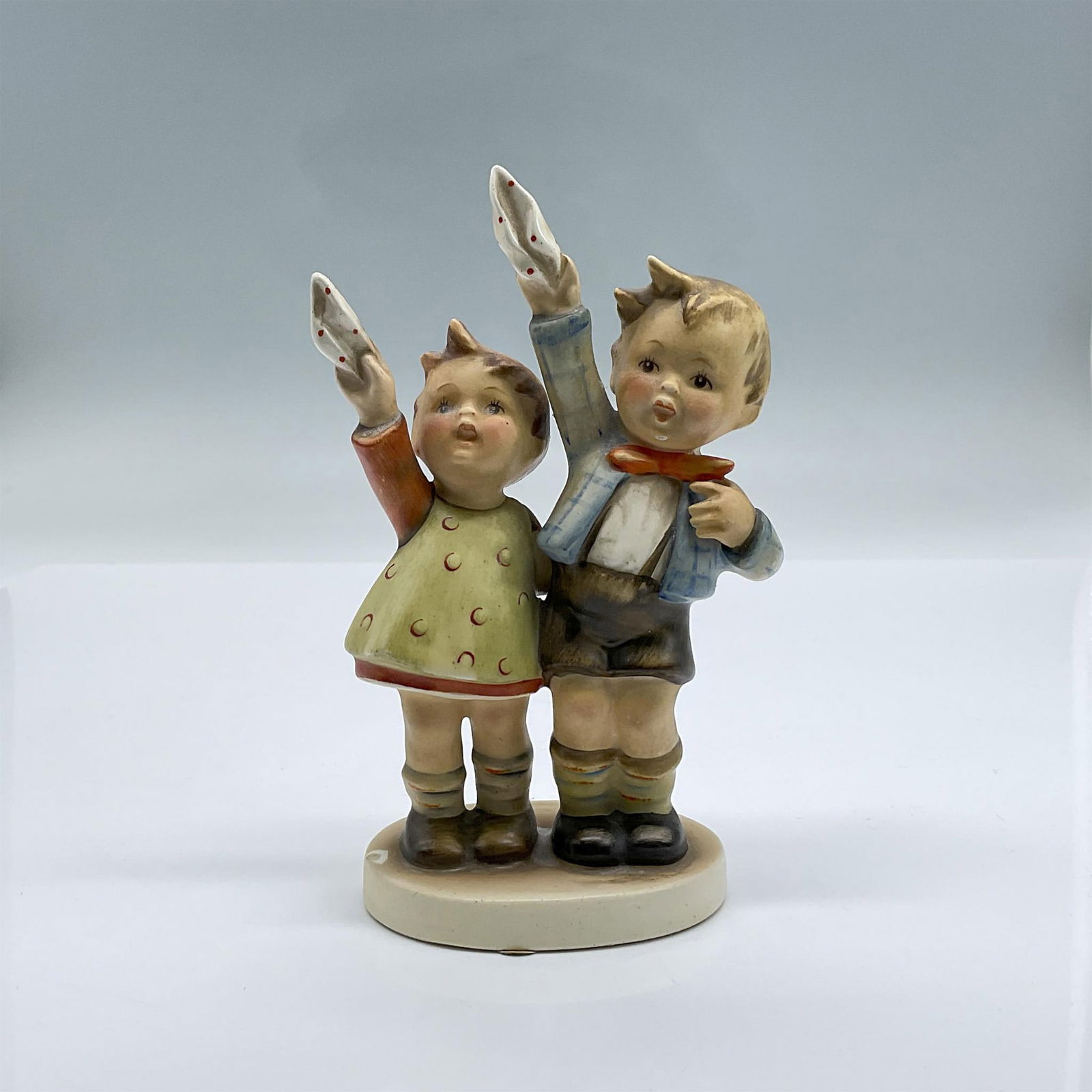 Goebel Hummel Figurine, Auf Wiedersenhen: This figure, whose name means goodbye in English is a beautiful hand painted porcelain of young siblings waving handkerchiefs. Backstamped with the Bumblebee V Germany. Issued: 1950 Dimensions: 3"L x