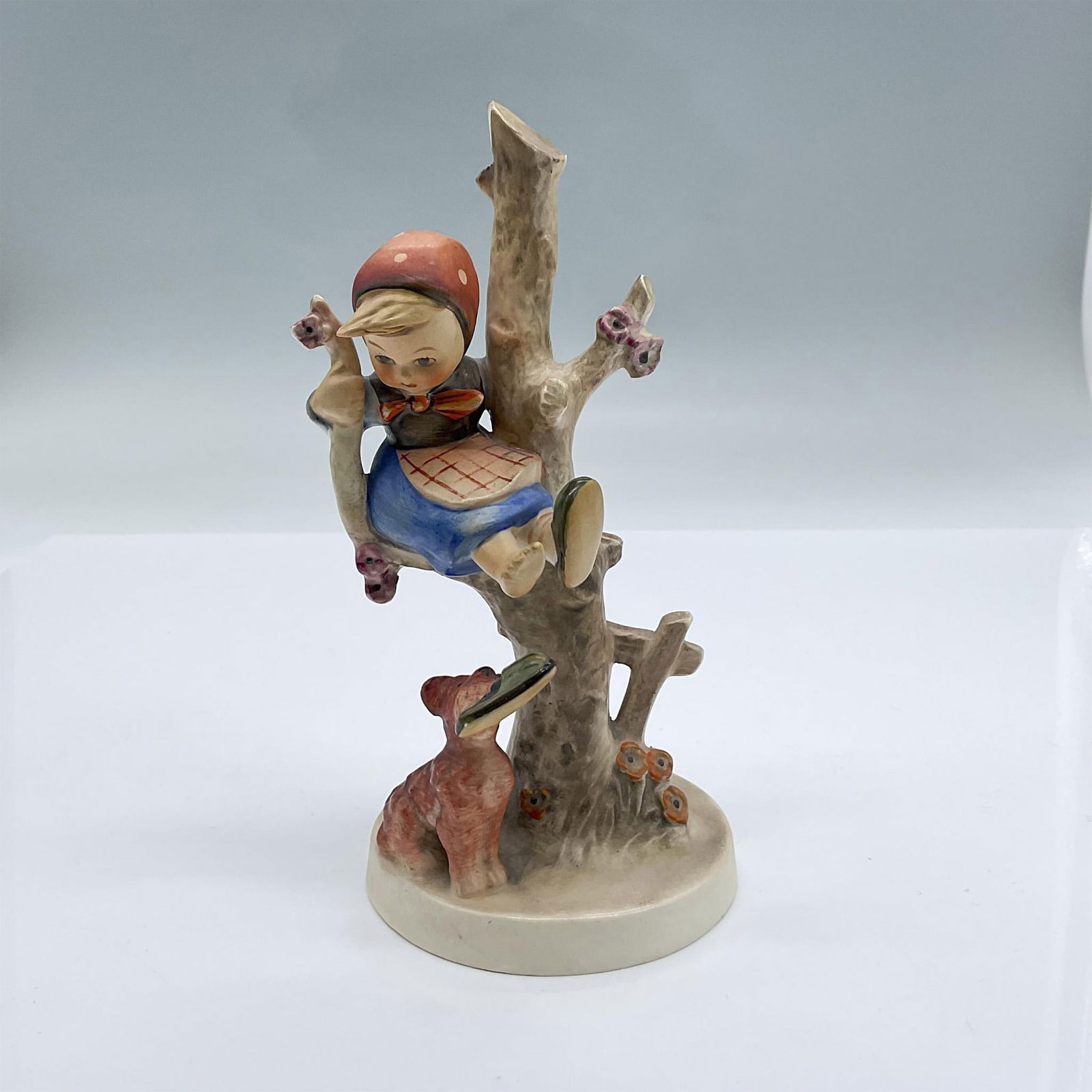 Goebel Hummel Figurine, Out of Danger: This item is beautifully hand painted from Germany. Features an adorable young child up in a tree sitting on a branch above the potentially dangerous dog at the base of the tree beside the extra flora
