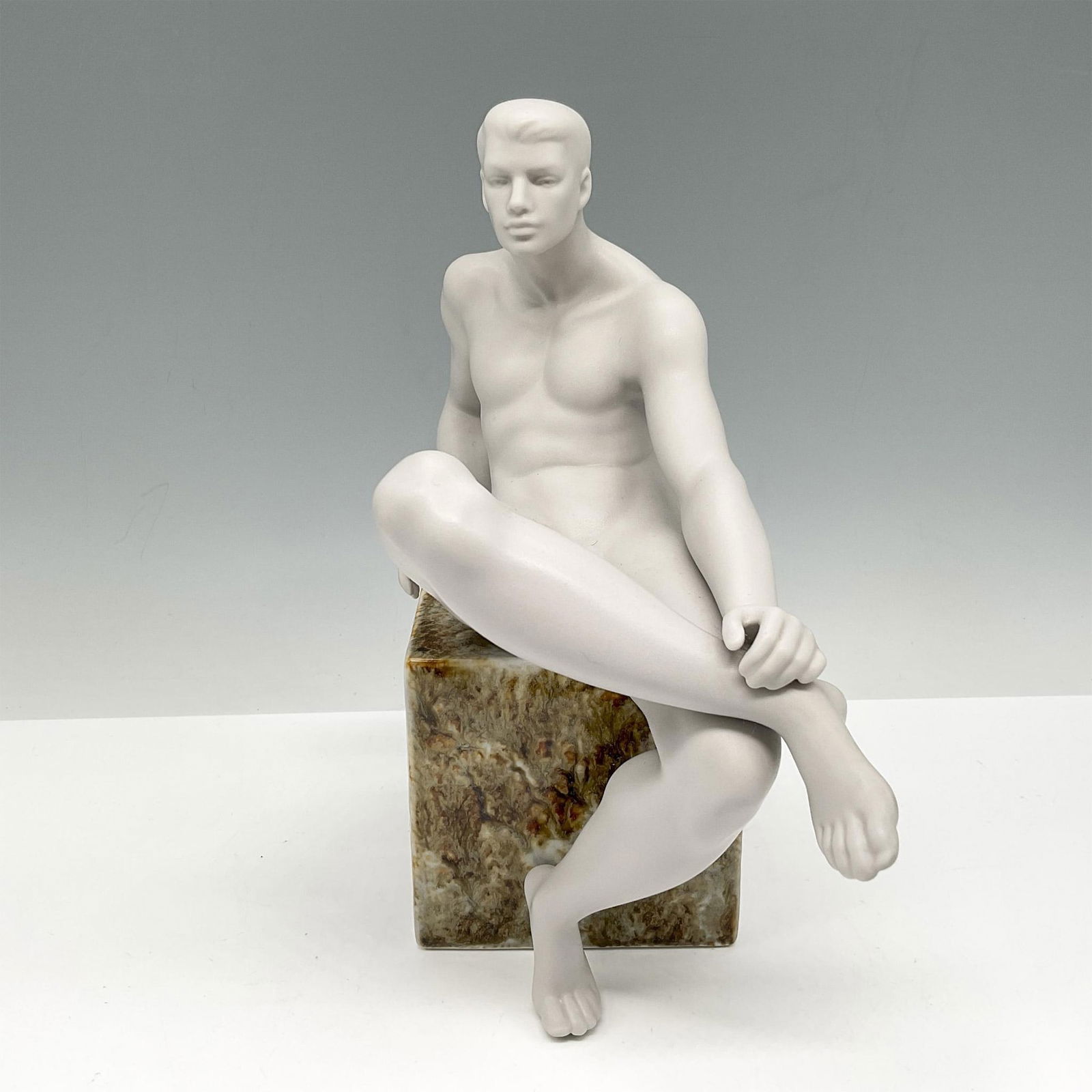 Lladro Porcelain Statue, Essence of Man I 1018147: Statue is part of a series of art pieces celebrating men. Monochromatic nude male reclining on cube stone. Lladro backstamp. Artist: Jose Luis Santes Issued: 2005-2008 Dimensions: 3.5"L x 8.5"W x 9"H