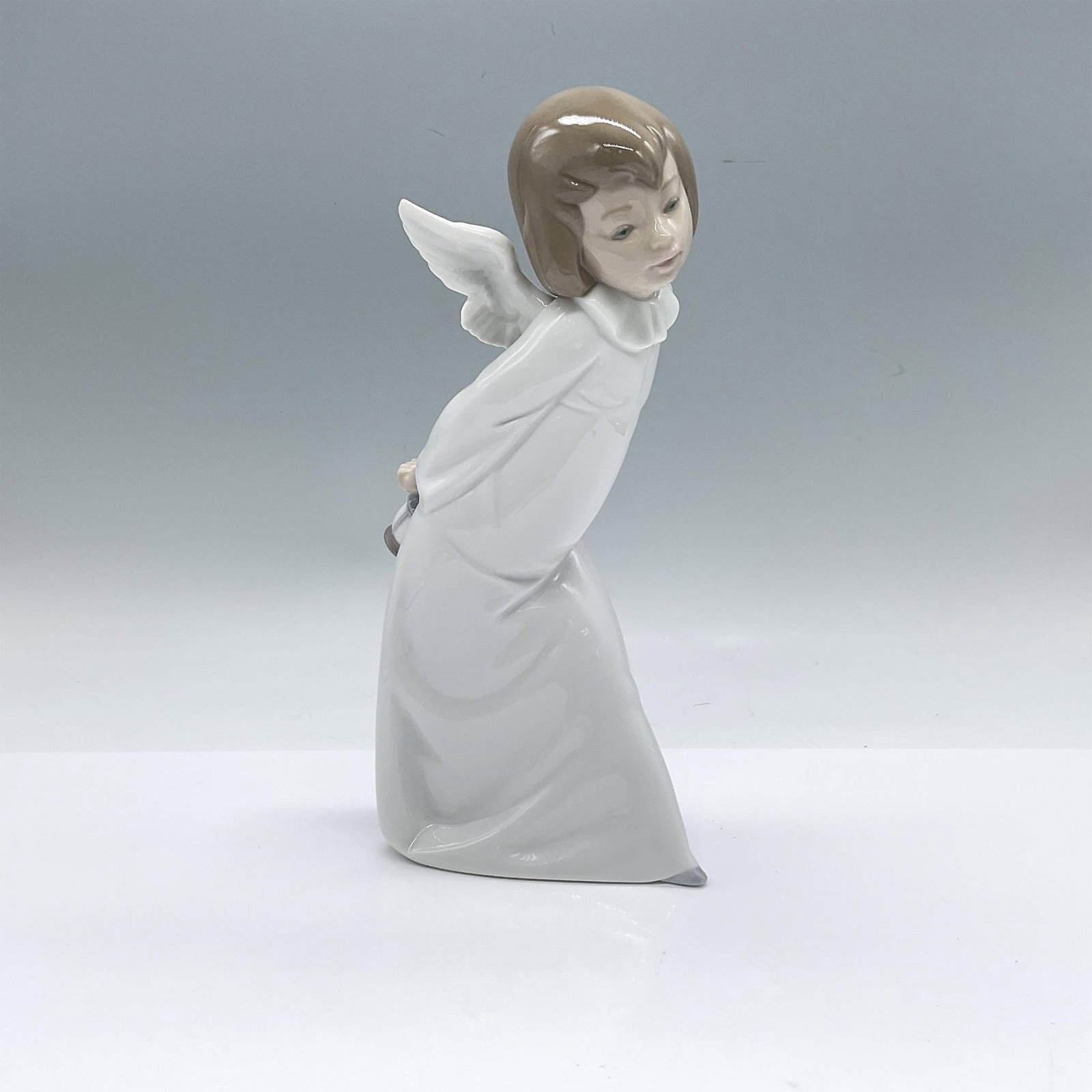 Lladro Porcelain Figurine, Cherub Smiling 1004960: Glossy figure of a young girl with white wings, holding a lantern and smiling. Lladro backstamp. Artist: Salvador Debon Issued: Late 20th to 21st century Dimensions: 5"L x 3.5"W x 9.5"H Manufacturer: 