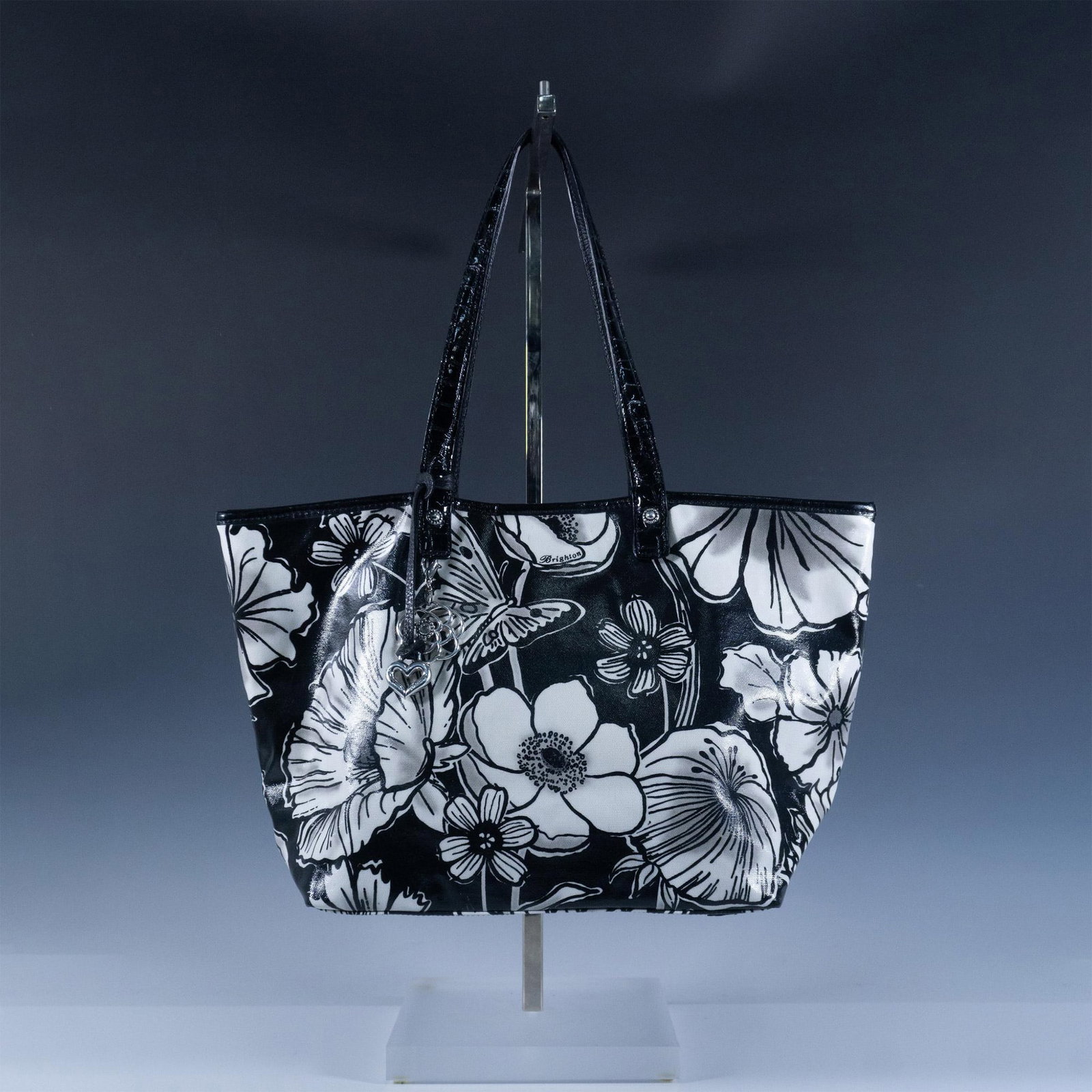 Brighton Black and White Floral Fabric Tote Handbag: This striking bag features big bold flowers in black and white. It has a protective lining over the fabric. The magnetic closure top opens to bright fabric lining with pockets. Black patent leather sh