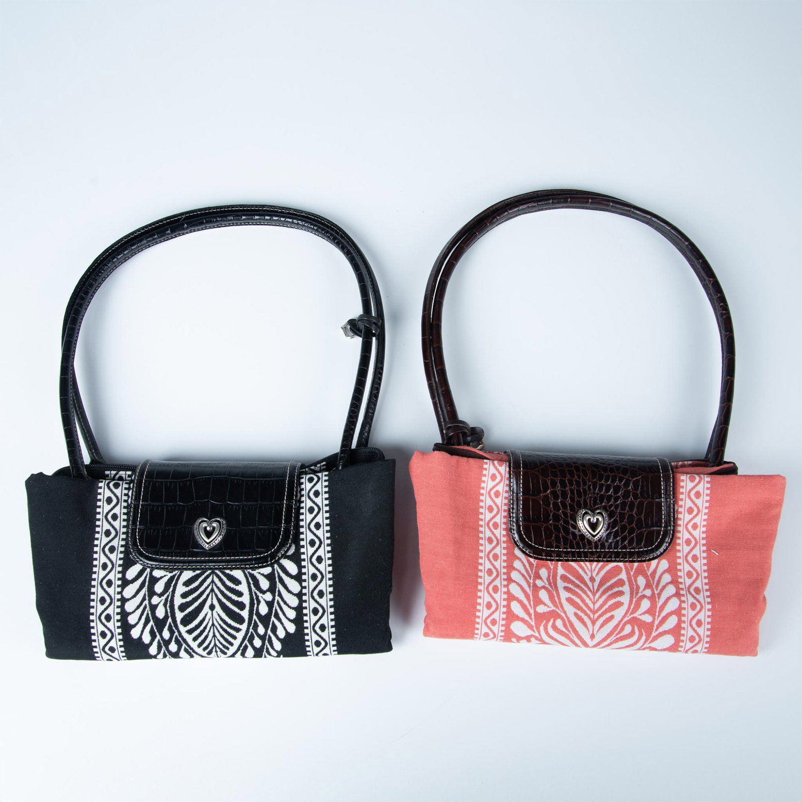 2pc Brighton Leather and Canvas Utility Bags: Two canvas bags in salmon and black decorated with floral and vine design. Button closure with top zipper and double leather handles. Brighton mark. Dust bag included. Issued: 20th century Dimensions: