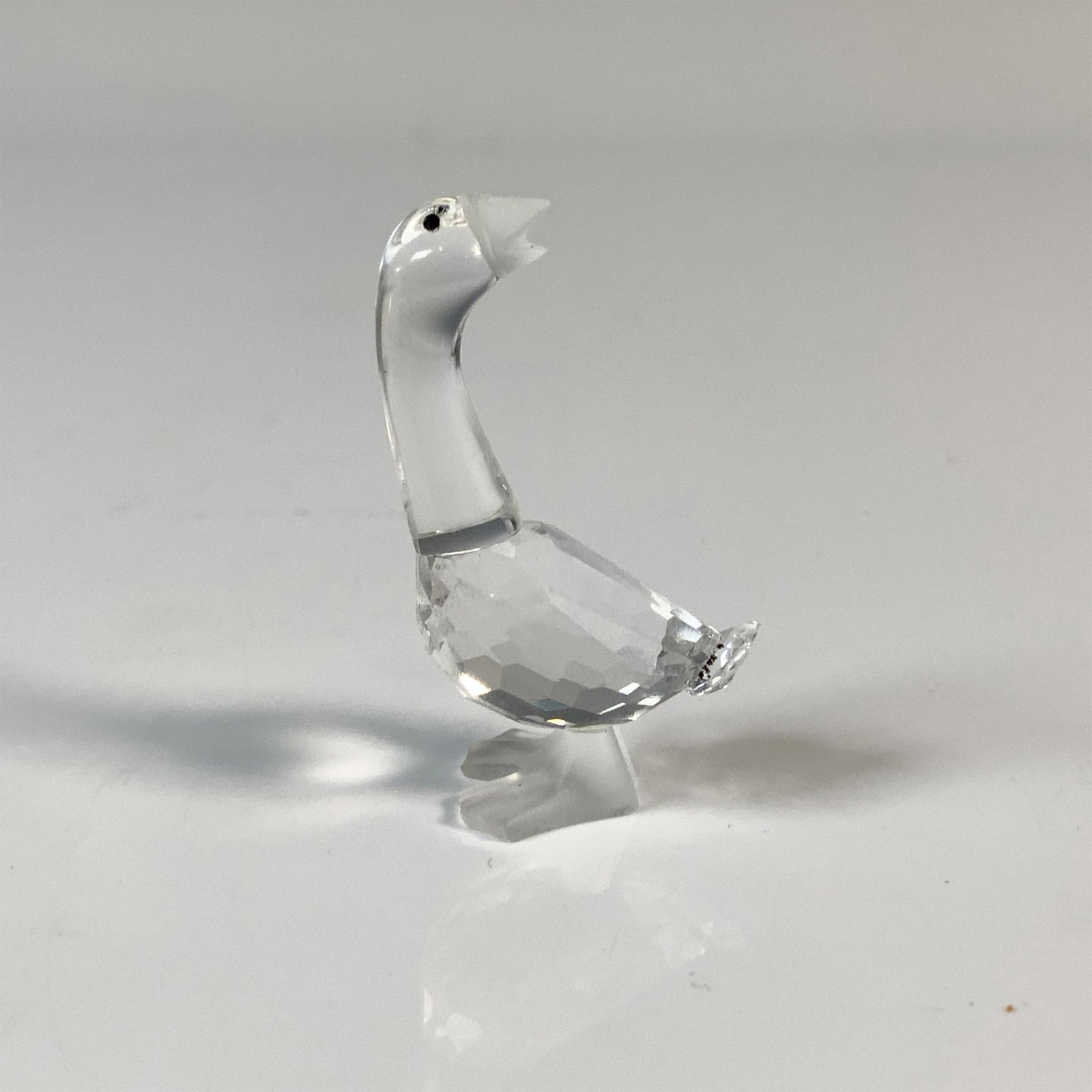 Swarovski Silver Crystal Goose Figurine, 7613 NR 000 004: A goose that is looking is looking behind. It has a clear cut crystal body, frosted bill and feet and black eyes. This item has its original box which measures 2.5"H x 3.25" dia. Acid etched Swarovski