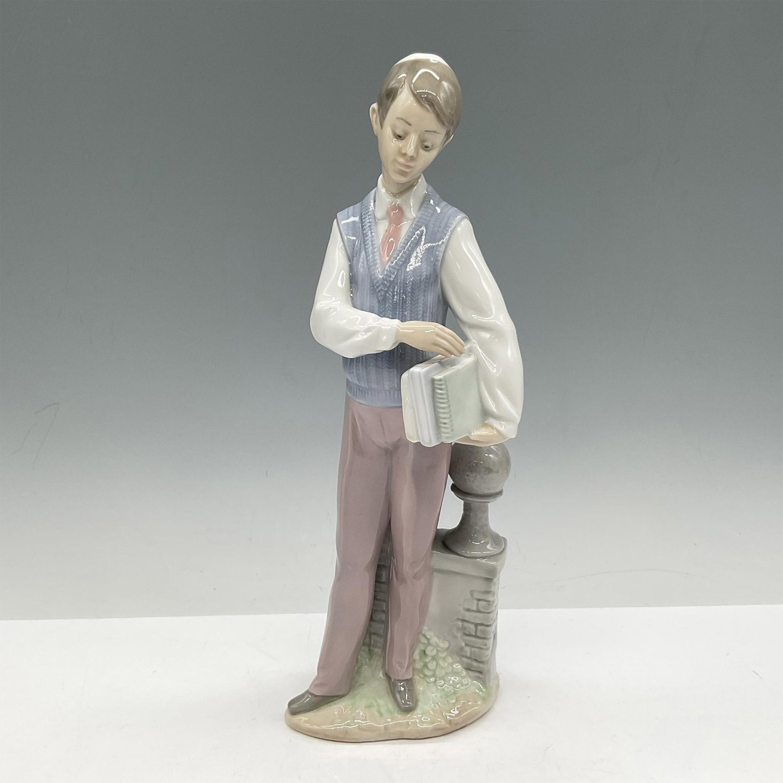 Hebrew Scholar 01006029 - Lladro Porcelain Figurine: Glossy Judaica figure dressed for school. Colored in white, blue and plum. Lladro backstamp. Artist: Francisco Polope Issued: 1993 Dimensions: 3.5"L x 2.25"W x 9.5"H Manufacturer: Lladro Country of O