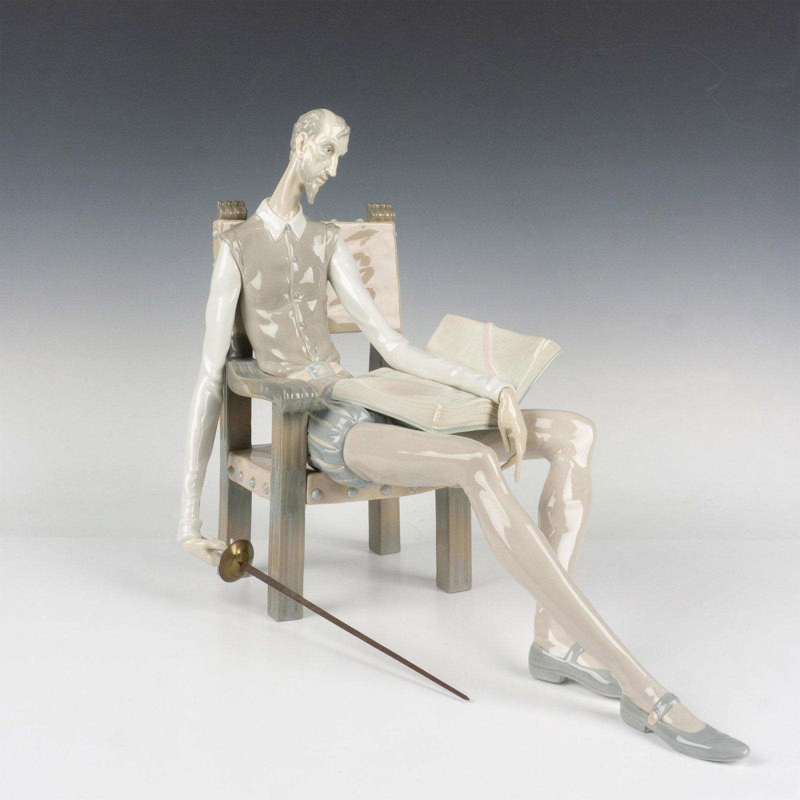 Don Quixote 01001030 - Lladro Porcelain Figurine: Glossy figure sitting in chair holding his sword. Lladro backstamp. Artist: Salvador Furio Issued: 1970 Dimensions: 10"L x 20"W x 19"H Manufacturer: Lladro Country of Origin: Spain