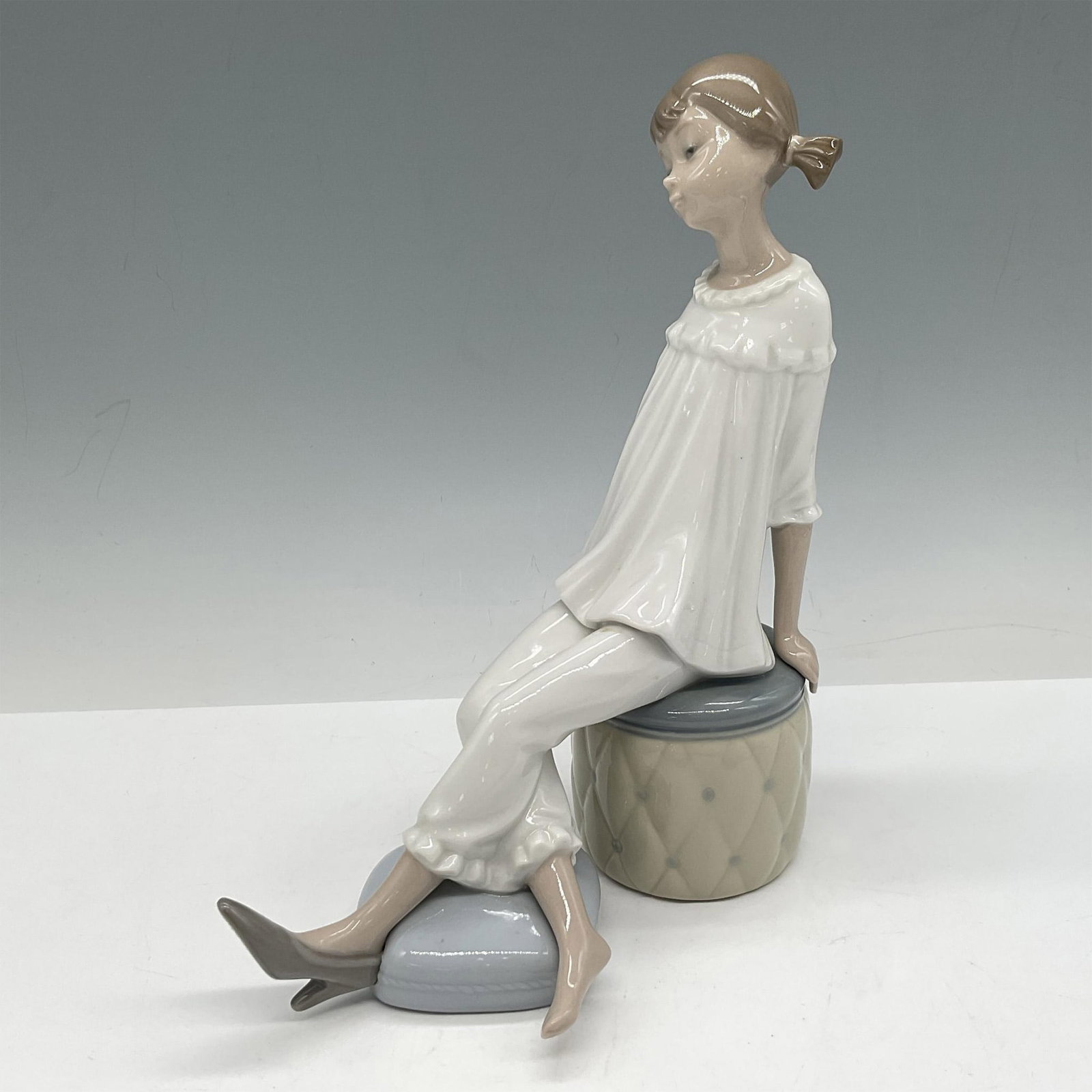 Girl with Mother's Shoe 1001084 - Lladro Porcelain Figurine: Glossy figure admiring the shoe. Lladro backstamp. Artist: Vincente Martinez Issued: 1969 - 1985 Dimensions: 3"L x 6"W x 7.5"H Manufacturer: Lladro Country of Origin: Spain