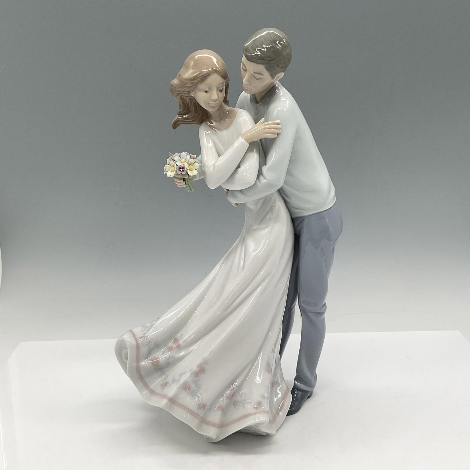 Love's Embrace 1006704 - Lladro Porcelain Figurine: Glossy figure of couple hugging, colored in soft light tones. 2000 Vanguard figurine. Lladro backstamp. Artist: Jose Javier Malavia Issued: 2000 Dimensions: 5.5"L x 7"W x 11.5"H Manufacturer: Lladro