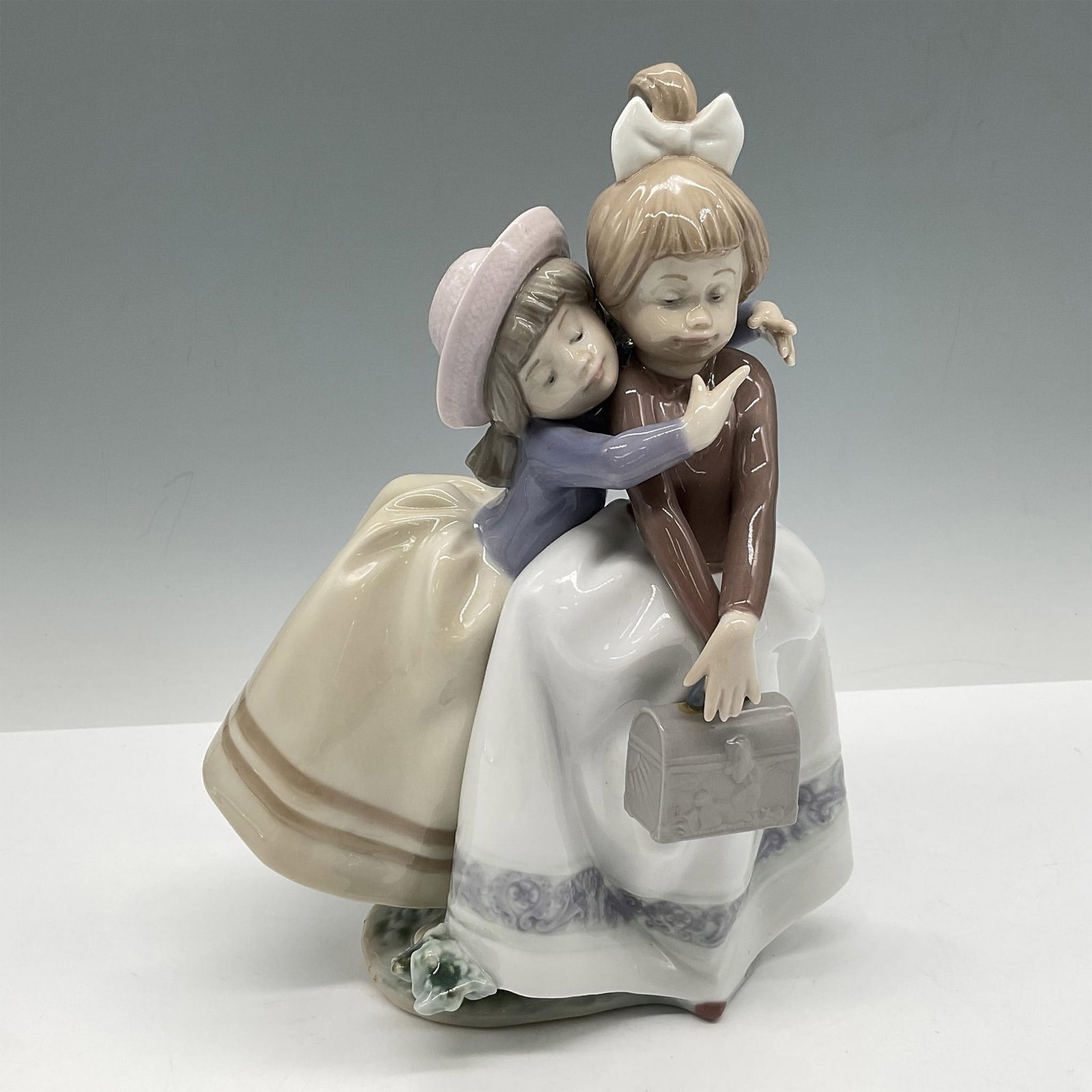 Sharing Secrets 1005720 - Lladro Porcelain Figurine: Glossy finish two adorable girls sharing a loving hug and secrets. Lladro backstamp. Artist: Antonio Ramos Issued: 1990 - 1997 Dimensions: 5.5''L x 6''W x 8.5''H Manufacturer: Lladro Country of Origi