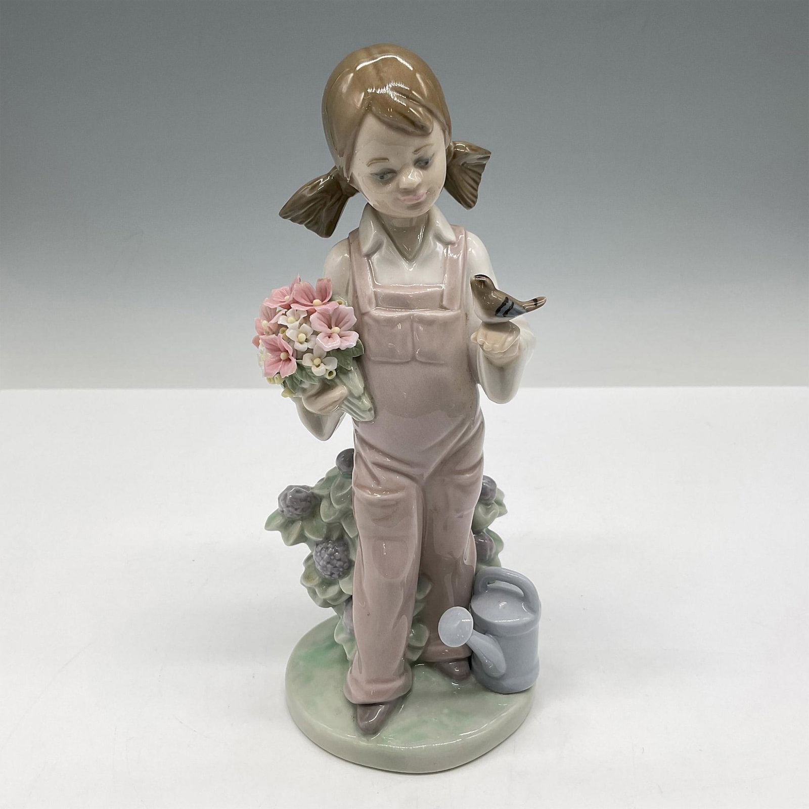 Spring 1005217 - Lladro Porcelain Figurine: Young girl holding flowers with a charming little bird perched on her hand depicts a return to Spring. Lladro backstamp. Artist: Juan Huerta Issued: 1984 Dimensions: 3.5"L x 3.25"W x 7.25"H Manufactur
