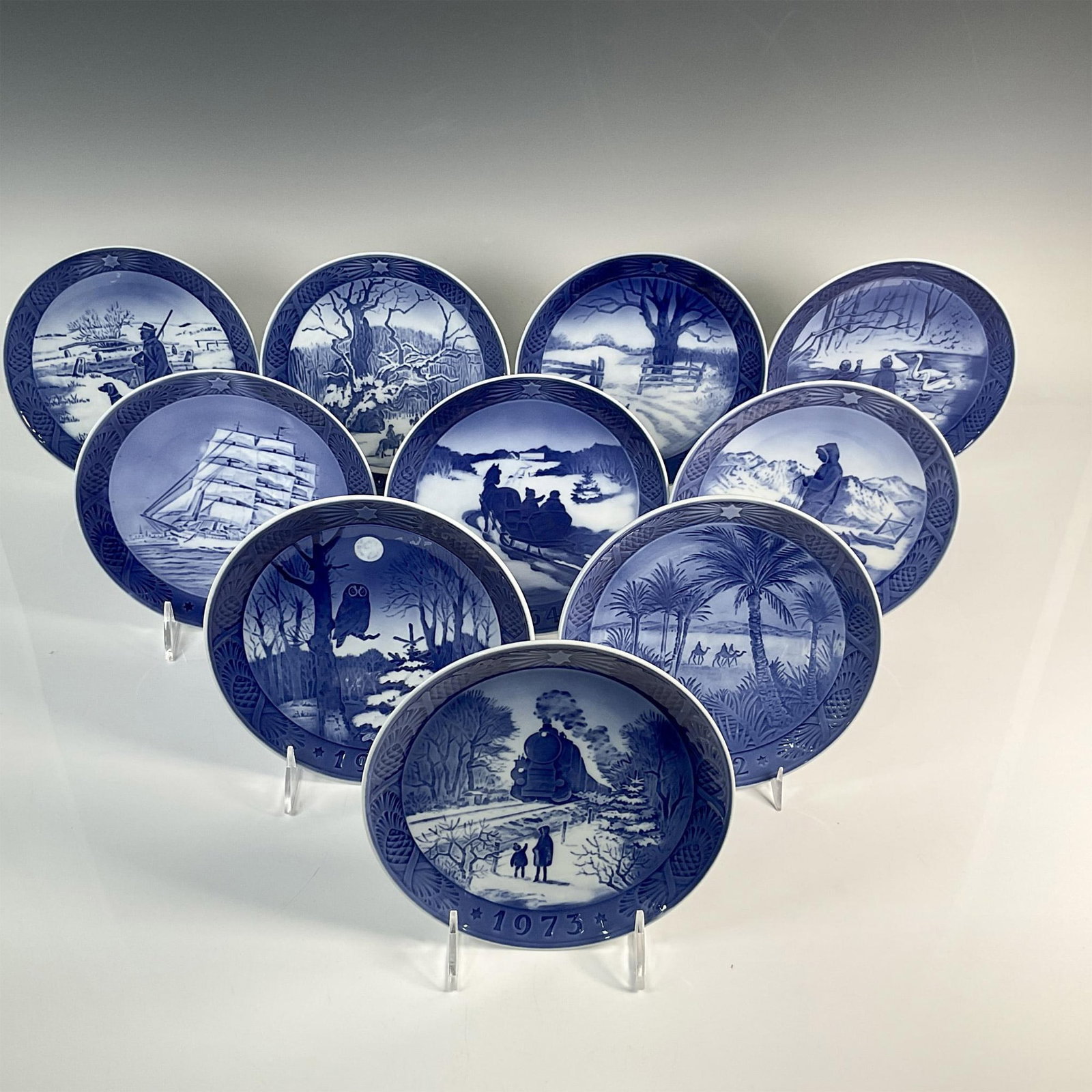 10pc Royal Copenhagen Porcelain Annual Plates: Ten exquisitely crafted porcelain plates, adorned in blue and white, depicting scenes of nature, the winter season, and cultural heritage. Includes: 1961, 1964, 1967, 1971, 1972, 1973, 1974, 1977, 197