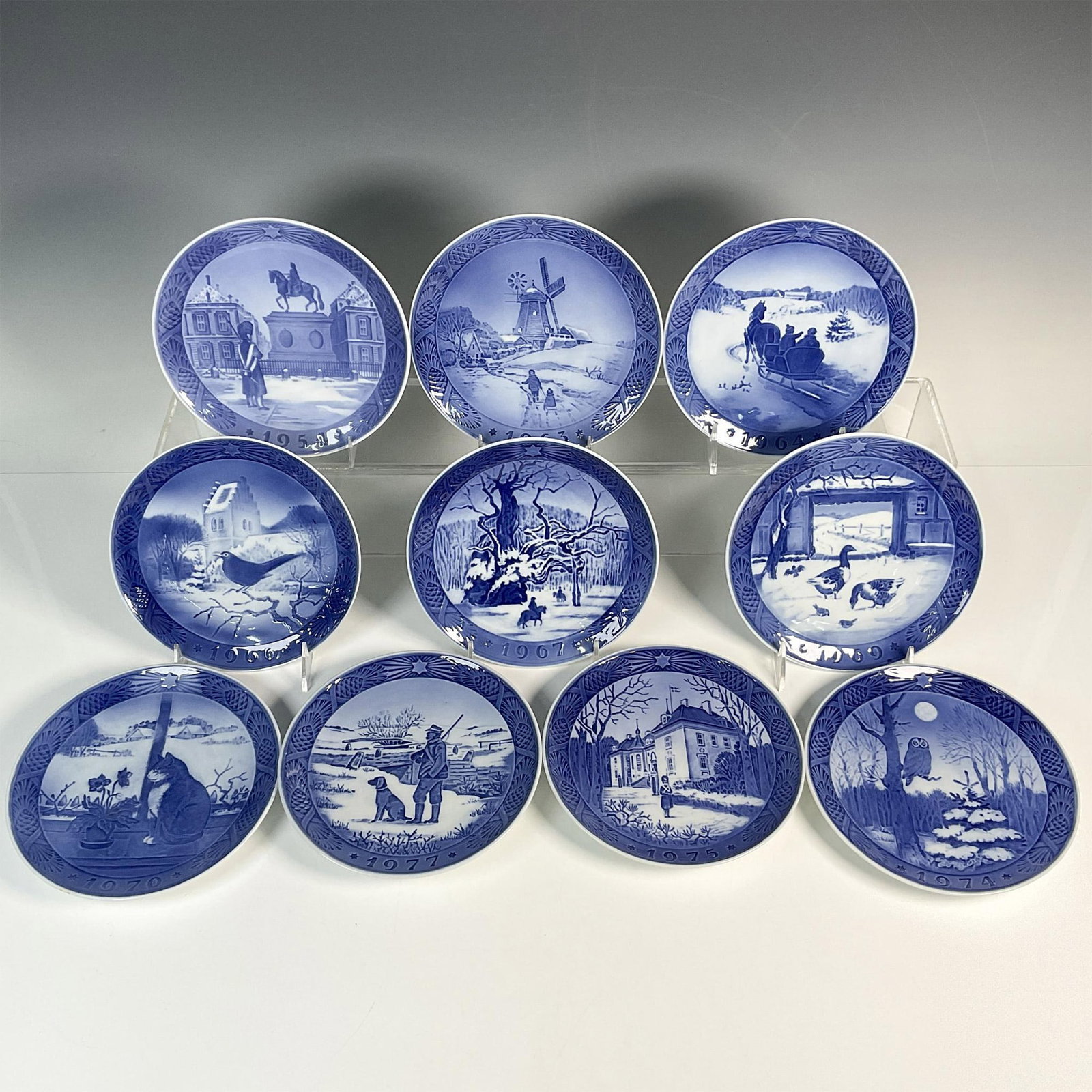 10pc Royal Copenhagen Porcelain Annual Plates: Ten beautifully crafted blue and white plates, decorated with a variety of winter scenes and Danish cultural heritage. Includes: 1954, 1963, 1964, 1966, 1967, 1969, 1970, 1974, 1975, 1977. Royal Copen