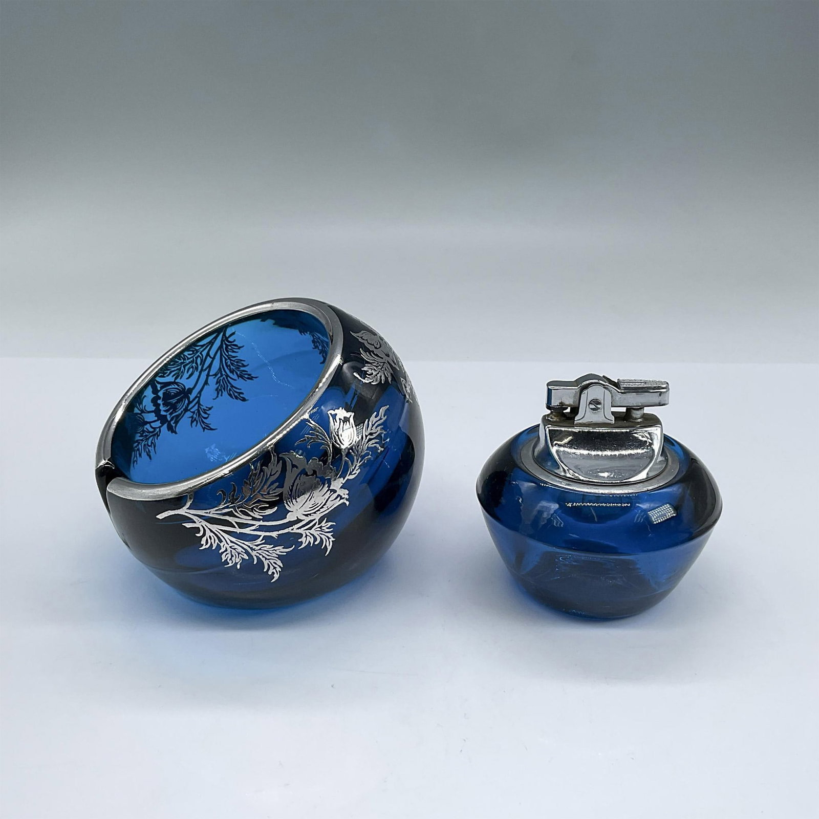 2pc Blue Glass With Silver Ashtray and Lighter: Round open ashtray with detailed silver floral overlay and rim 3"H x 4" dia. Removeable lighter from glass base. Dimensions: See Description