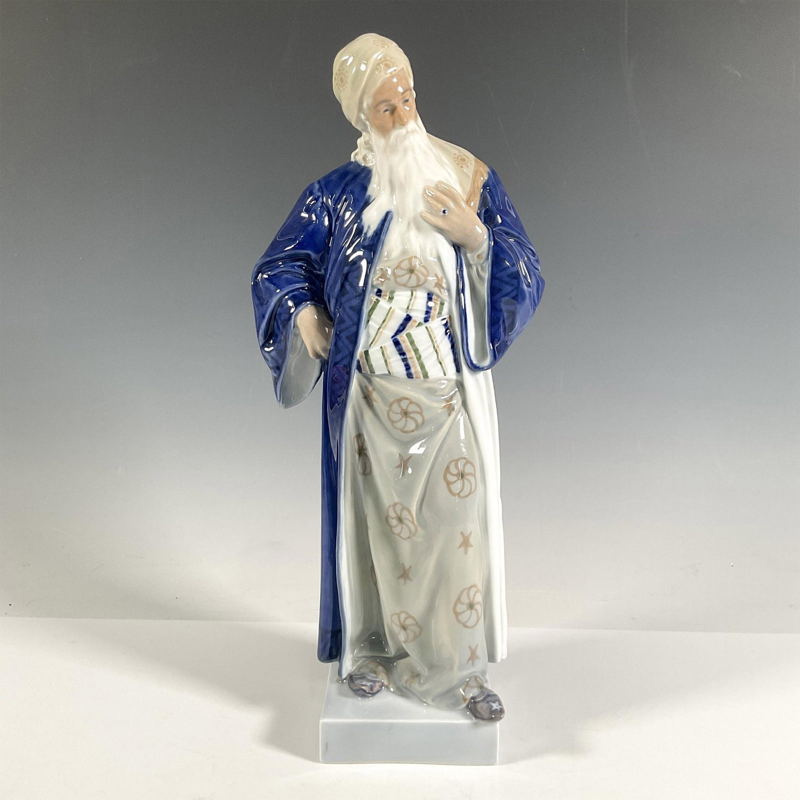 Royal Copenhagen Porcelain Figurine, Nathan the Wise 1413: A man dressed in a blue robe, adorned with a white and green outfit underneath, complemented by a long, distinguished white beard. Glossy finish. Royal Copenhagen backstamp. Marked 1413. Dimensions: 6