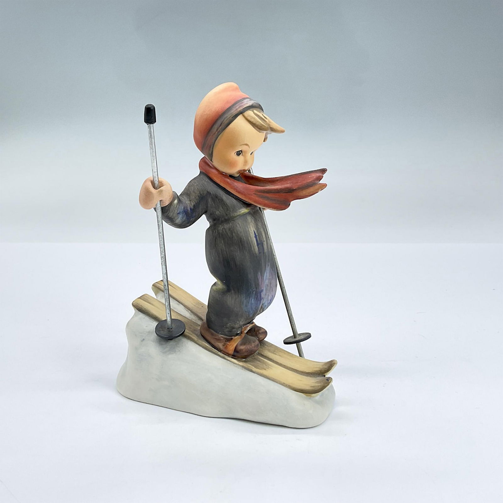 Goebel Hummel Porcelain Figurine, Skier 59: Hand painted figure of a boy wearing skis and a ski suit holding ski poles. Goebel backstamp. Dimensions: 4"L x 2.5"W x 5.25"H Manufacturer: Goebel Hummel Country of Origin: Germany