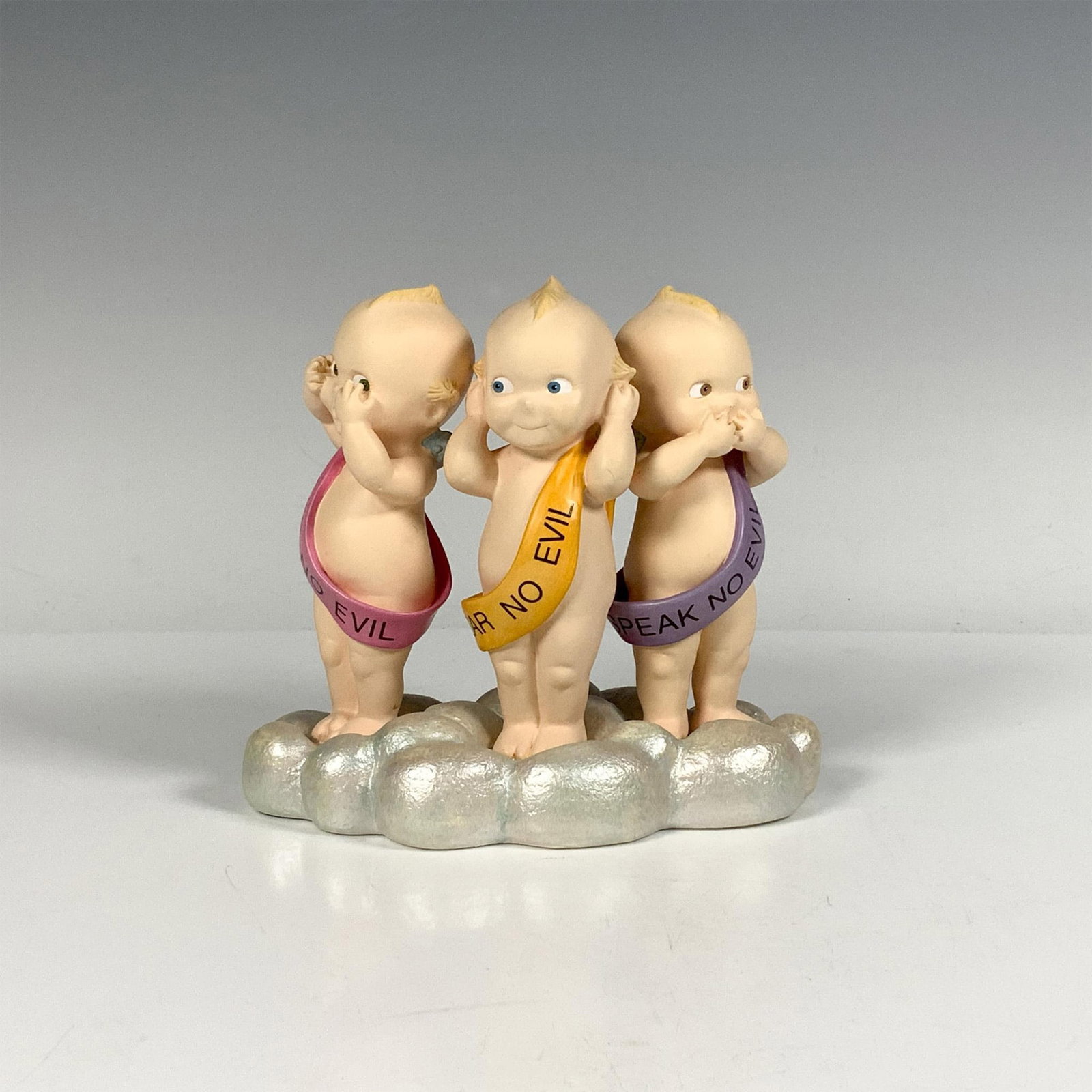 Jesco Kewpie Figurine, Angelic Trio: Three angelic babies standing on a cloud, wearing sashes with the words See No Evil, Hear No Evil, and Speak No Evil. Issued: 1999 Dimensions: 5.25"L x 3"W x 4.75"H Manufacturer: Jesco