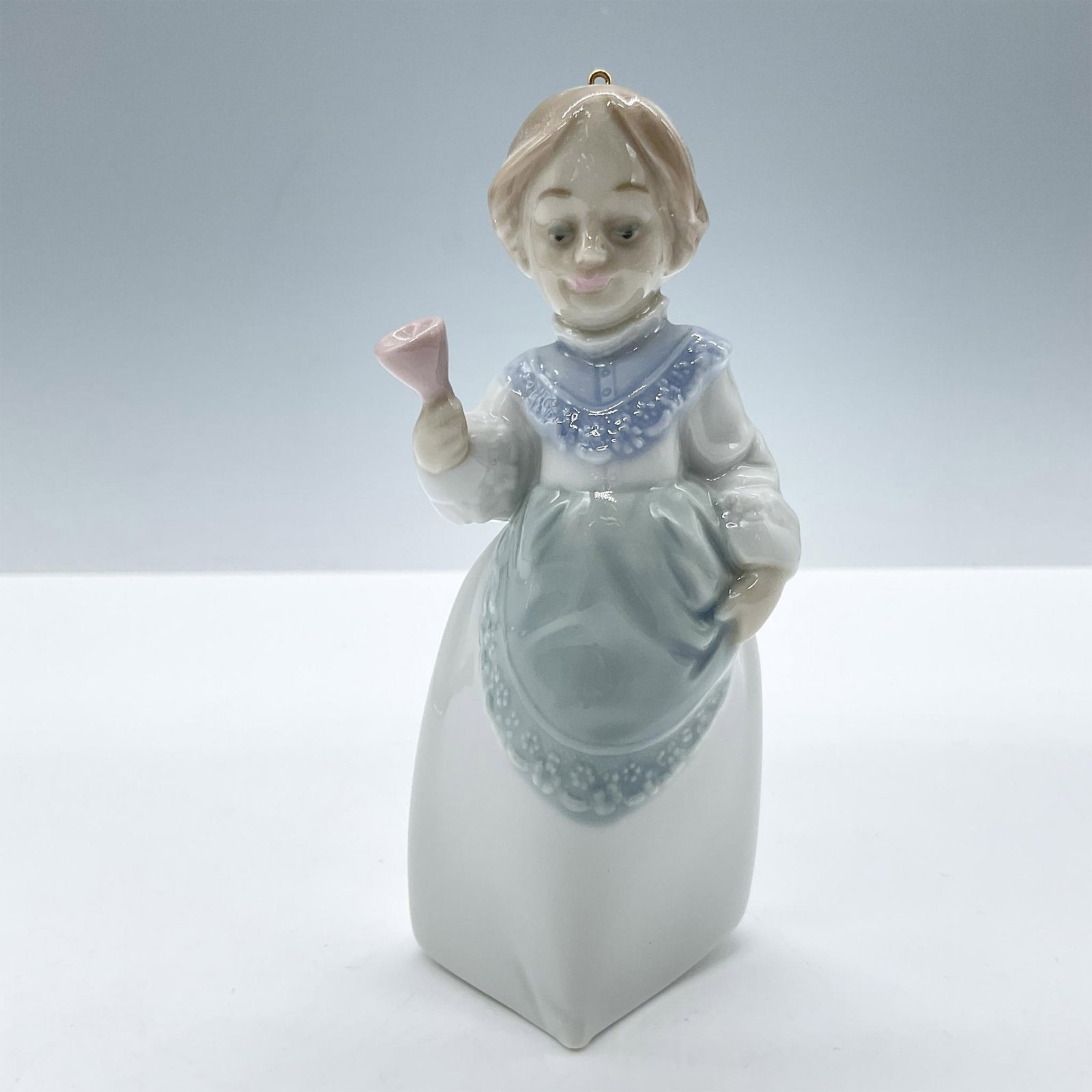 Mrs. Claus 1005939 - Lladro Porcelain Ornament: Glossy porcelain. Features pale blue and green colors, holds a pink bell. Lladro backstamp. Includes the original box, dimensions: 4.25''L x 5''W x 2.5''H. Artist: Joan Coderch Issued: 1992 - 1993 Dim