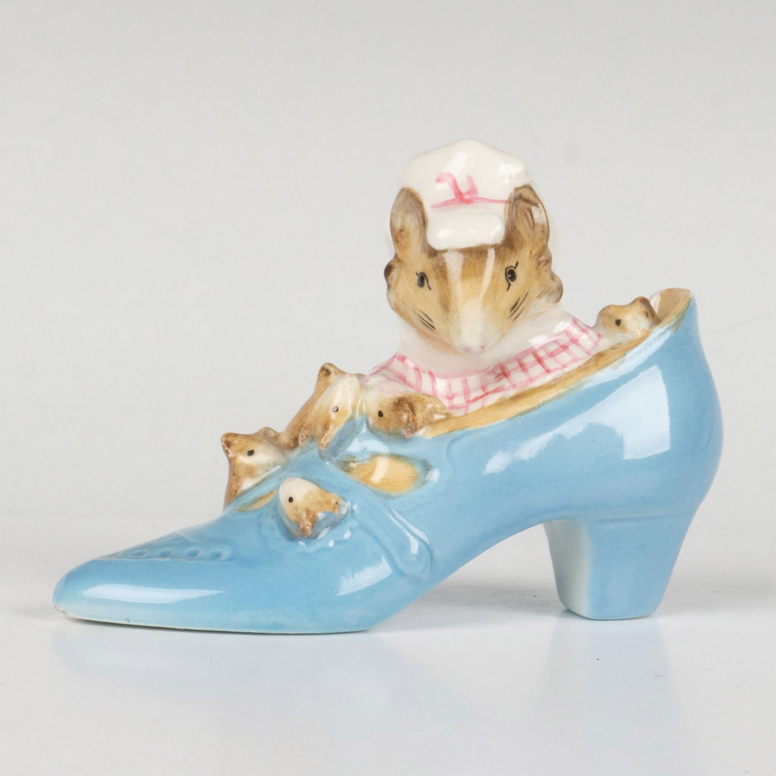 Beatrix Potter Figurine, Old Woman who Lived in a Shoe Gold: Glossy finish. Features a blue shoe with a lady mouse and her babies. Beswick Beatrix Potter Gold Oval backstamp. Issued: 20th century Dimensions: 3.75''L x 1.5''W x 2.75''H Manufacturer: Beswick Coun