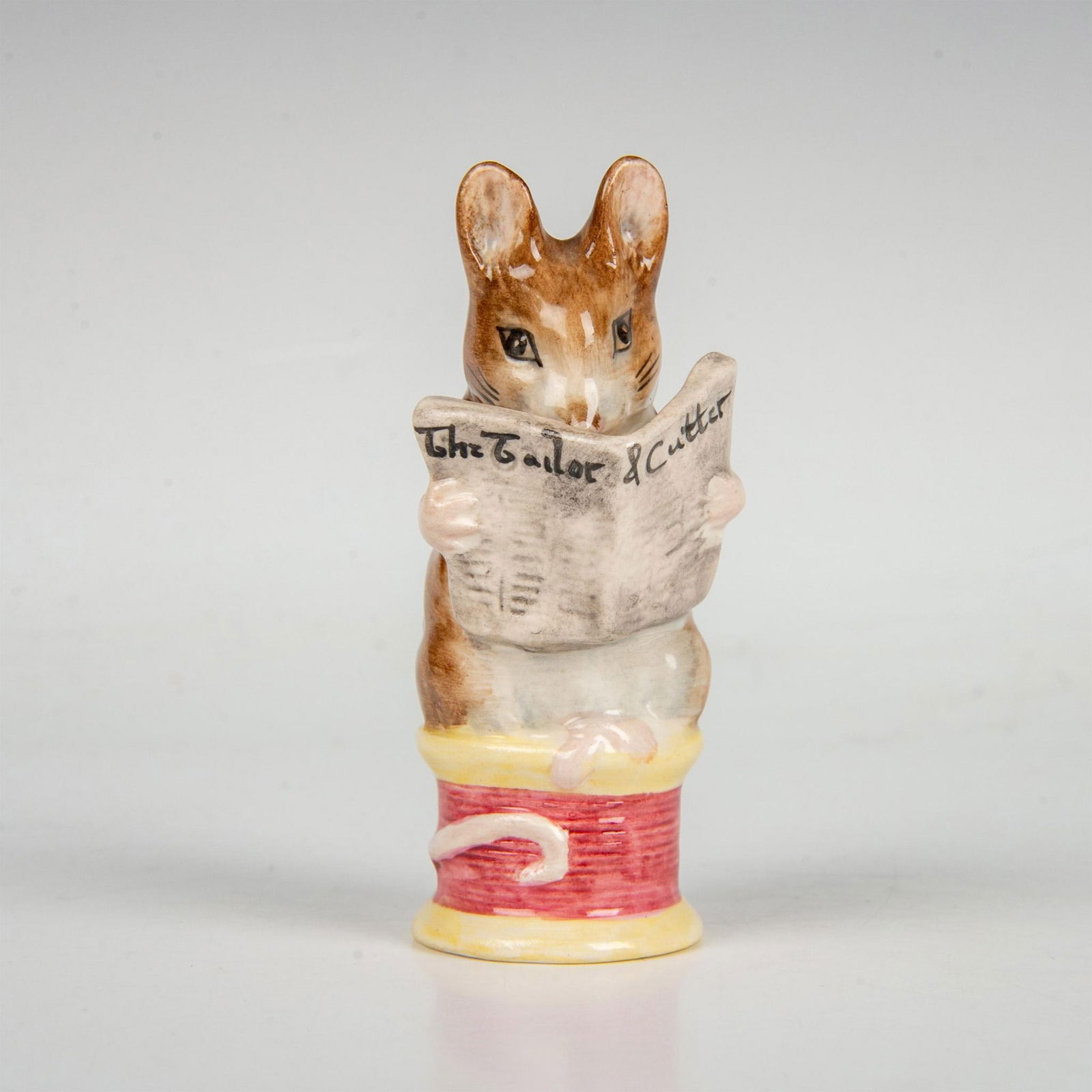 Beswick Beatrix Potter Figurine, Tailor of Gloucester: An adorable mouse sitting on a magenta thread. Includes the original box, dimensions: 2''L x 2.75''W x 5.5''H. Beswick backstamp. Issued: 20th century Dimensions: 1.25''L x 1.75''W x 3.75''H Manufactu