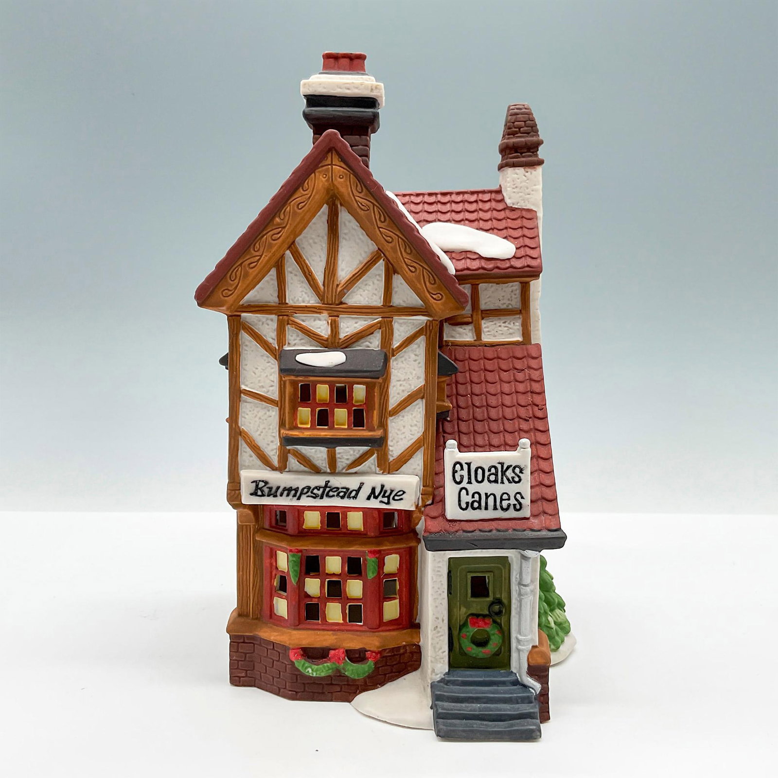 Department 56 Figure, Bumpstead Nye Cloaks and Canes Lighted: Part of the Dickens' Village Series. Hand-painted porcelain, depicting quaint wattle and daub style storefront. This item has its original box with dimensions: 8"L x 7"W x 9.5"H. Light unit included. 
