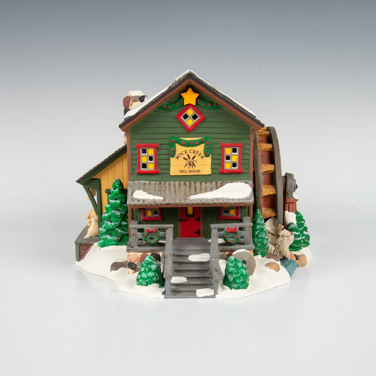 Dept 56 Snow Village Collection, Rock Creek Mill House: Handpainted matte porcelain figure modelled as a quaint house with a mill wheel on the side and snow seen all around. Department 56 backstamp. Includes bulb with wire. Includes original box 12"L x 11"