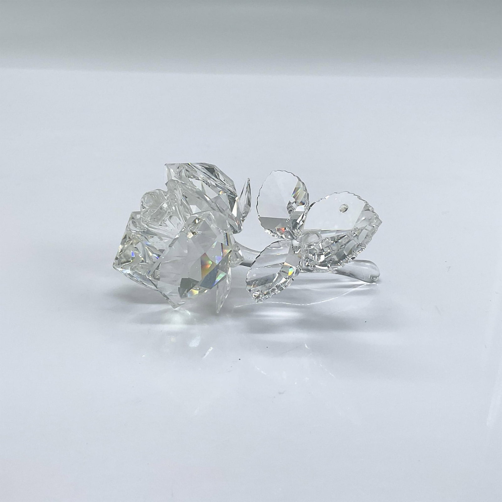 Swarovski Crystal Figurine, Rose: Sparkling clear faceted crystal figure of a rose with leaves. Swarovski etched mark. Includes original box 4.75"H x 6"dia. Issued: 1993-2007 Dimensions: 3.25"L x 2"W x 1.25"H Manufacturer: Swarovski C