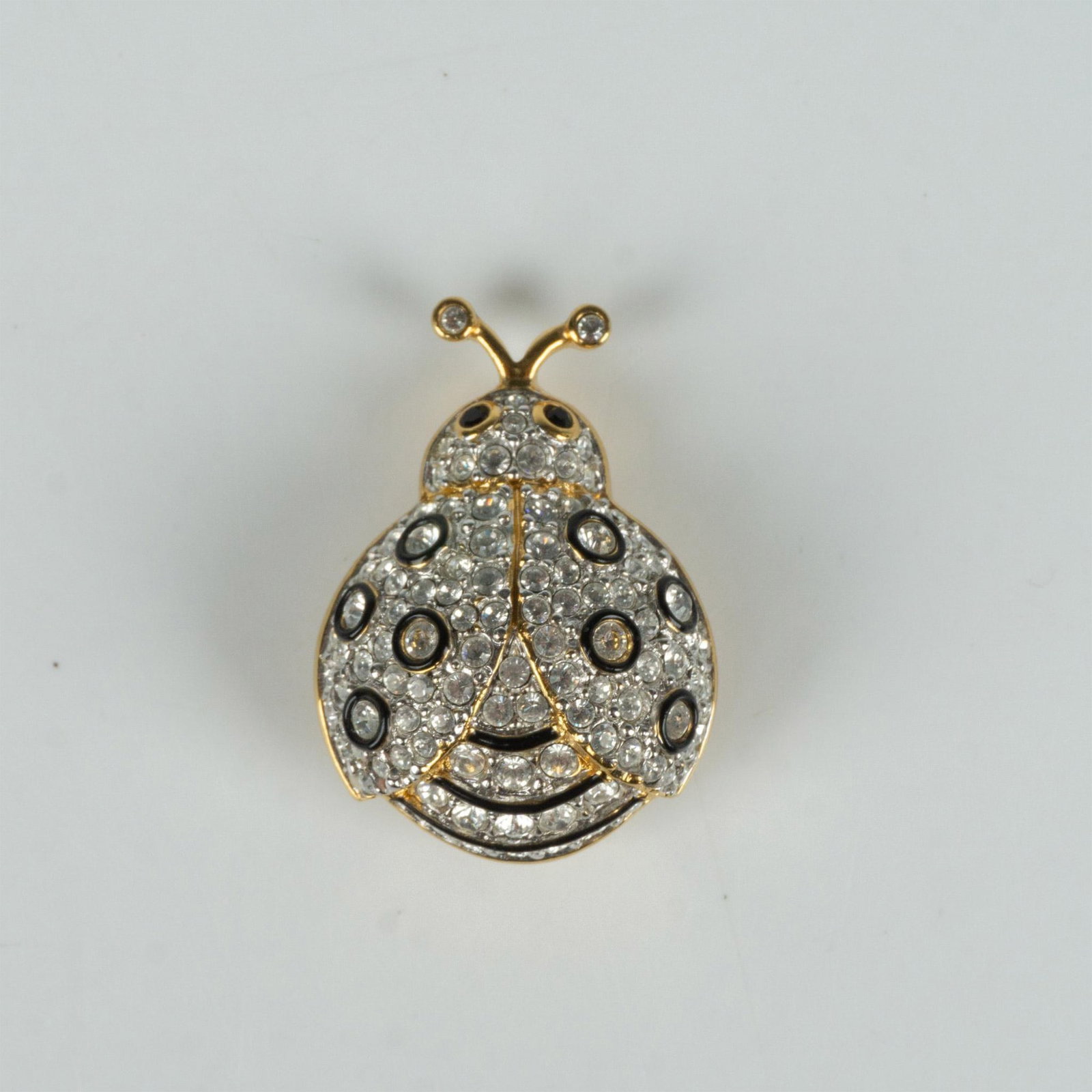 Swarovski Crystal Black and Gold Ladybug Brooch Pin: Sparkling gold metal brooch featuring round clear crystals with black enamel accents and black crystal eyes. Swarovski hallmark on the back. Dimensions: 1.25"L x 1"W Manufacturer: Swarovski Country of