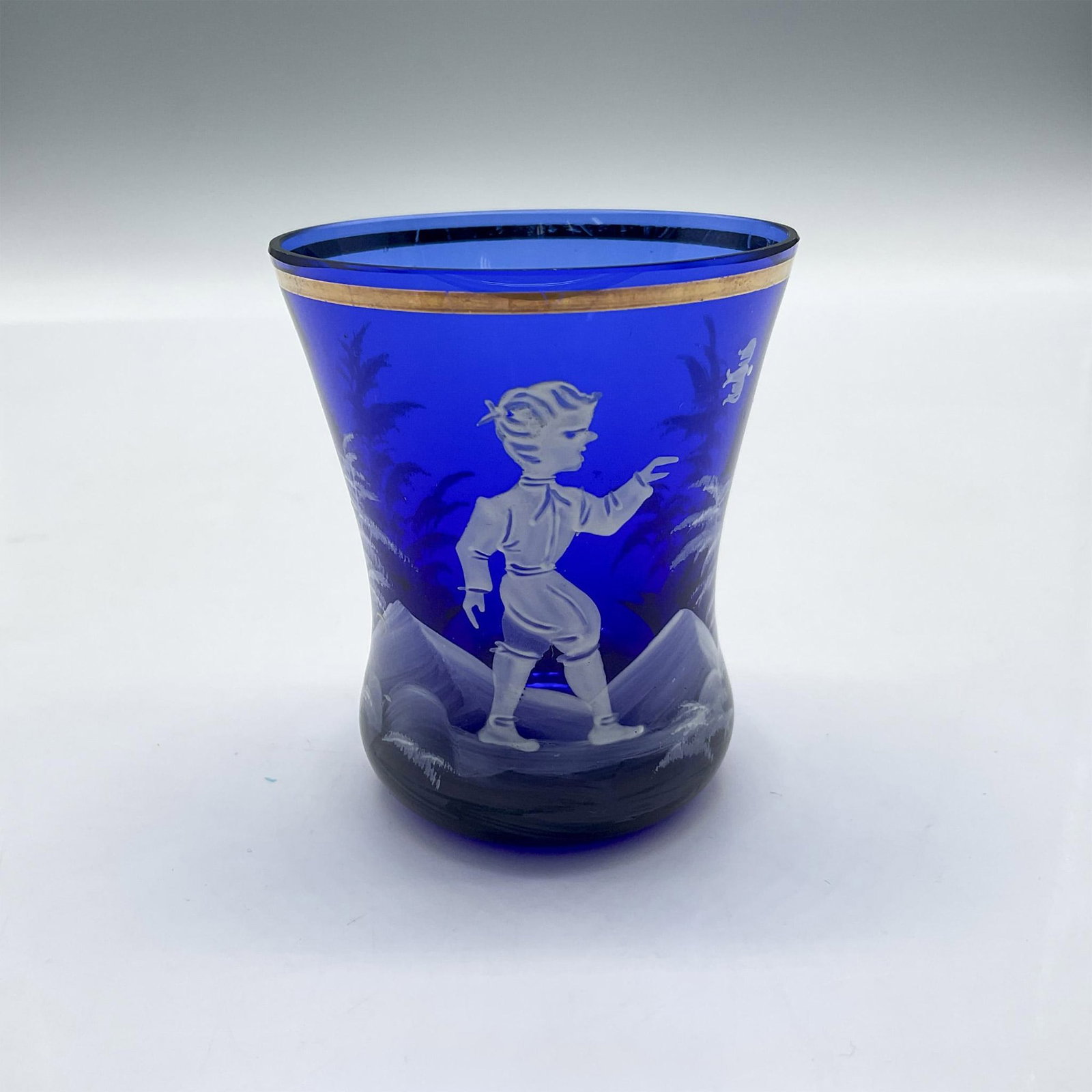 Mary Gregory Cobalt Blue Boy & Bird Toothpick Holder: Deep blue glass with gilt rim and hand painted design in white of boy with bird. Issued: 20th century Dimensions: 2.75"H x 2.25" dia. Manufacturer: Mary Gregory