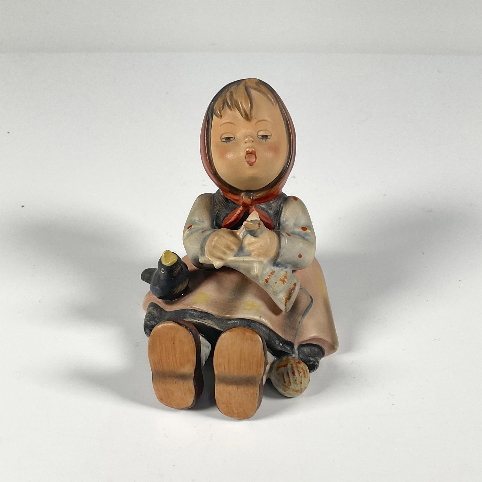 Goebel Hummel Porcelain Figurine, Happy Pastime: Hand painted porcelain figurine of a seated little girl with a black bird. Impressed marks 59 and 97. Backstamp in black Western Germany and stylized bee in a V in blue. Issued: 20th century Dimension
