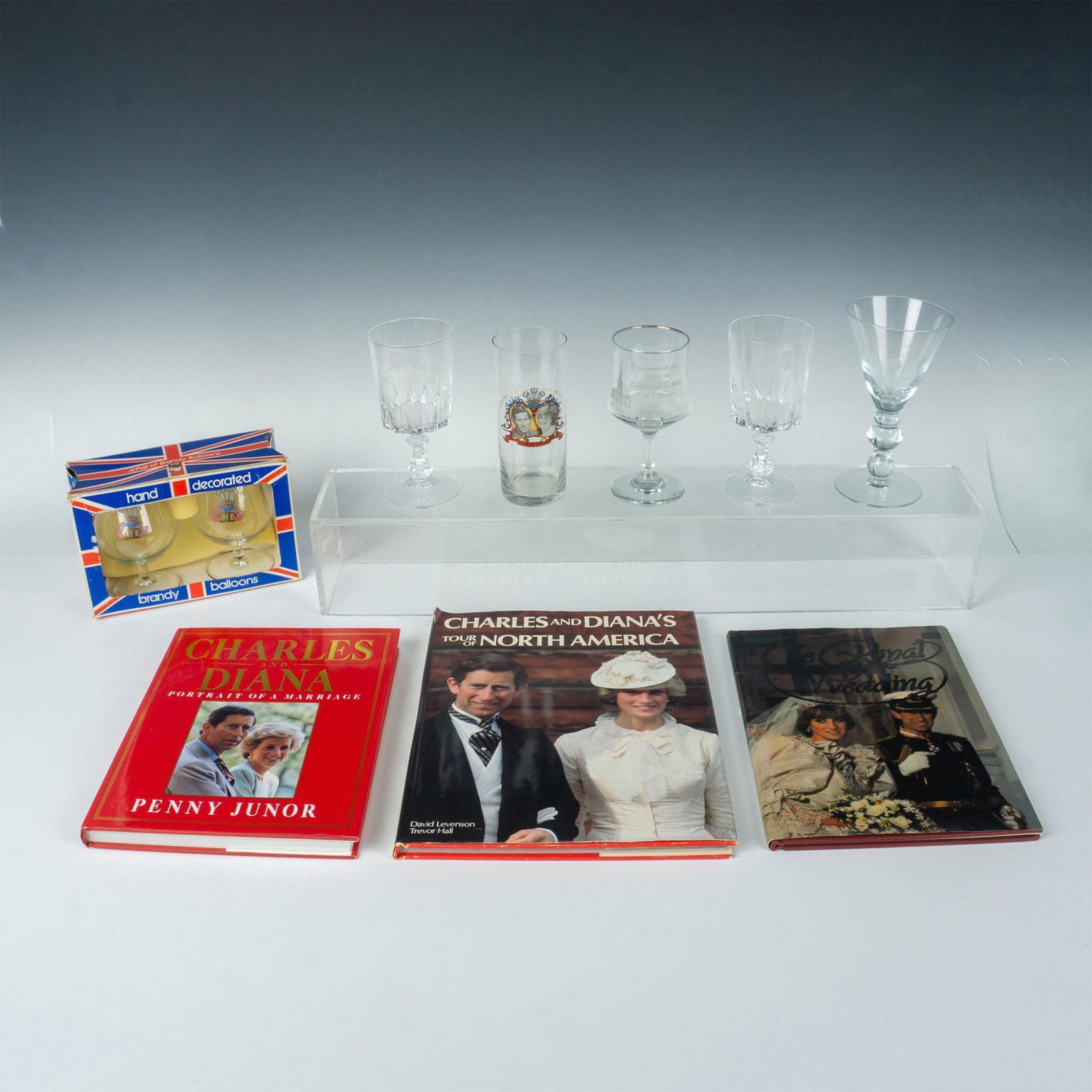 10pc Prince Charles and Diana Memorabilia: Lot includes Hand decorated brandy balloons in original box 8"L; Two Diana & Charles St. Paul's goblets 6"H; commemorative goblet 6"H, high ball glass 6"H and wine goblet 7"H of wedding 1981; and 3 bo