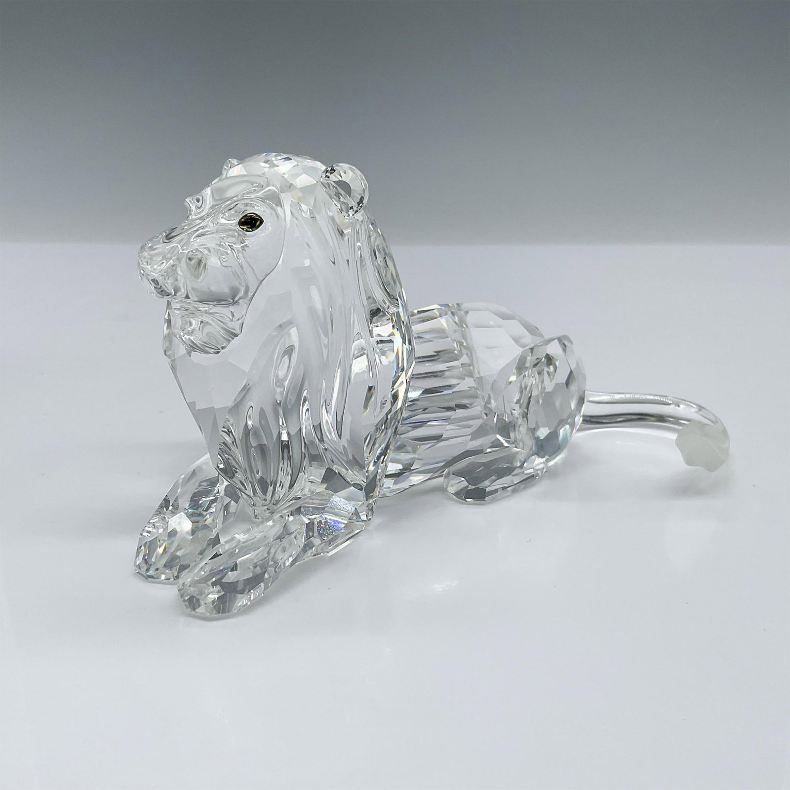 Swarovski Clear Crystal Figurine, Lion 185410 with Base: Final piece of the Inspiration Africa trilogy. Annual edition lead clear crystal lion seated gracefully with frosted crystal tip of tail. Swarovski etched backstamp. This item has a base included that