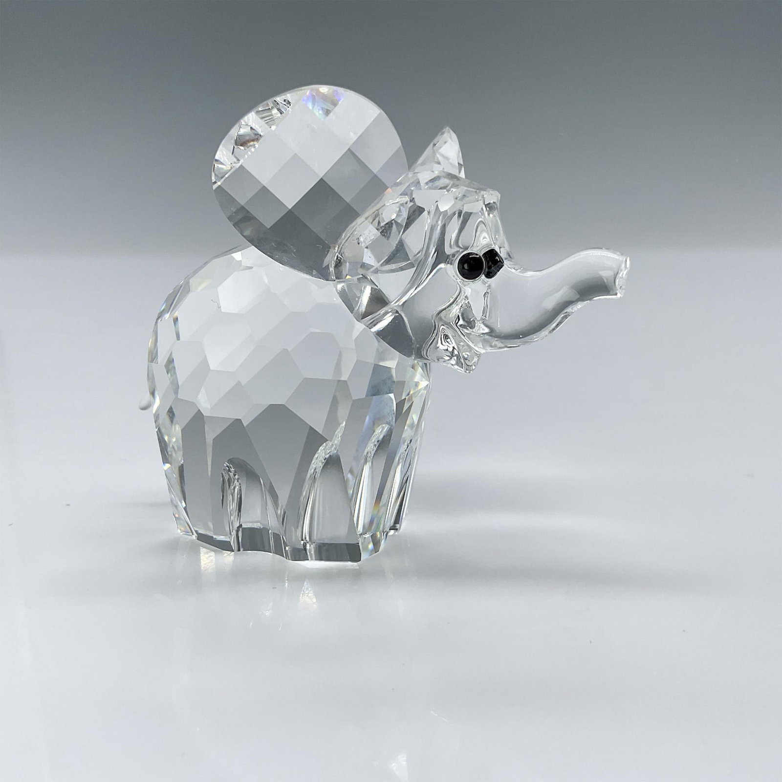 Swarovski Crystal Figurine, Elephant 015169: This Swarovski crystal elephant was part of the African Wildlife series. It is made from clear crystal with black eyes and a frosted crystal tail. Swarovski backstamp. Artist: Adi Stocker Issued: 1988
