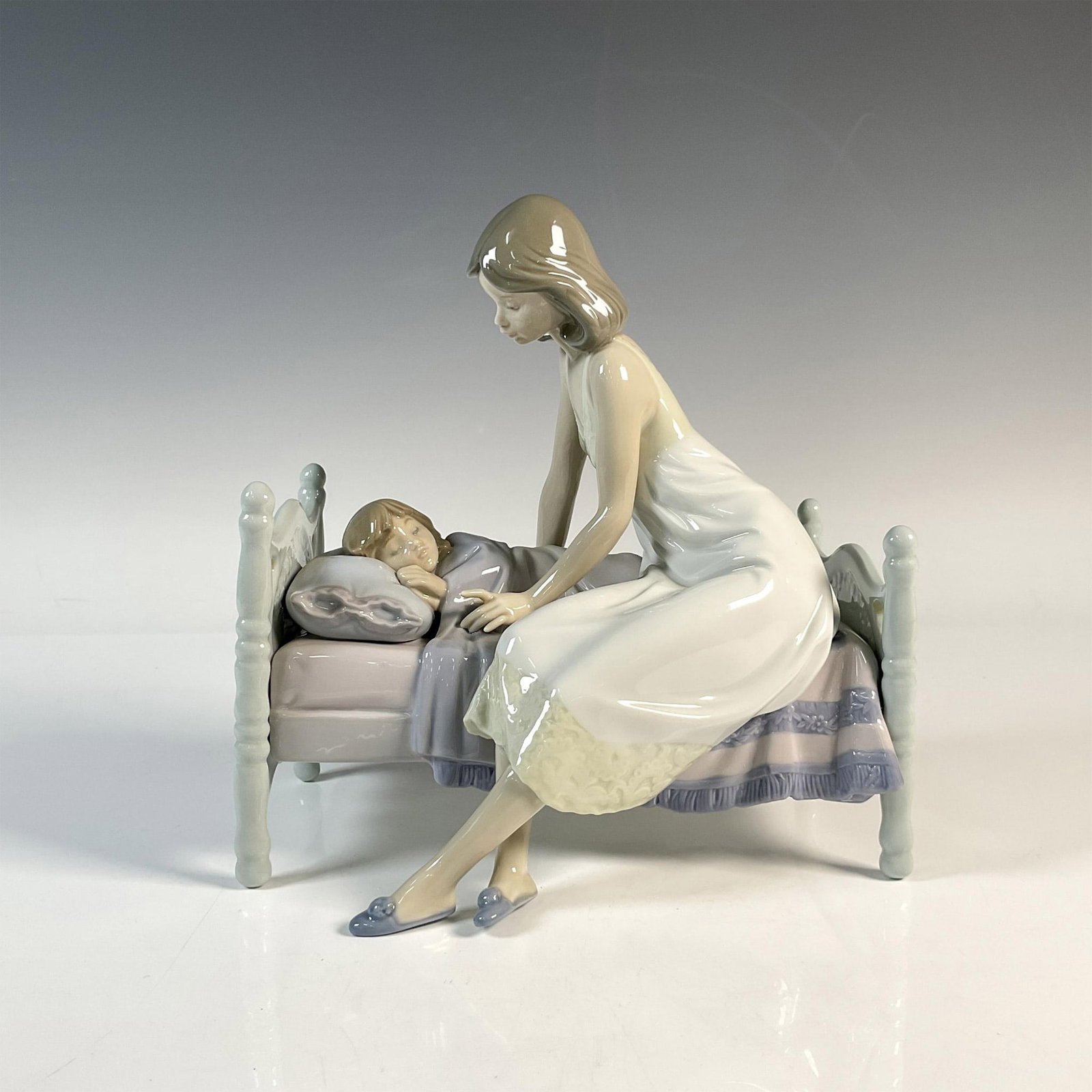 Sleep Tight 01005900 - Lladro Porcelain Figurine: Glossy figure of mother and child at bedtime. Lladro backstamp. This item has its original box: 11"L x 13"W x 11"H. Artist: Joan Coderch Issued: 1992 - 1997 Dimensions: 7.5"L x 4.5"W x 8"H Manufacture